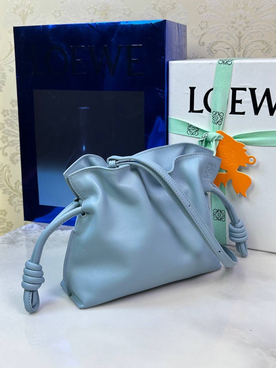 Flamenco clutch-NEW ✦迷你✦ 尺寸：𝟐𝟐.𝟓-𝟏𝟖-𝟗𝐜𝐦 型号：052030灰蓝色 ❤️mini flamenco clutch bag 可手拿亦可优雅斜挎 云朵般温暖亦轻盈的造型如此简单，💯耐看💯不会out的款式！ ❤️包袋采用进口小牛皮，手感如羊皮般细腻柔软，却比羊皮更加结实耐用，麂皮内衬 ❤️品牌标志性绳结设计，收紧袋口就是小福袋造型，超Q，看着不大实际超会装😇