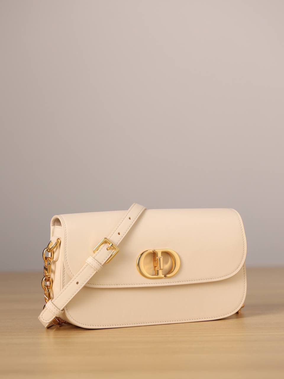 30 MONTAIGNE AVENUE 手袋 灰象牙色光面牛皮革👜✨ 独家渠道货 独家蒙田腋下包白色珐琅扣 尺寸：22.5 x 12.5 x 6.5 厘米 这款 30 Montaigne Avenue 手袋采用典雅的设计，提升此经典系列的格调。 采用黑色光面牛皮革精心制作，圆角翻盖曲线精致，饰以复古金色饰面金属 CD 扣环，灵感源自 Christian Dior 香水瓶的封口。 背面饰以压花 30 Montaigne 标志，搭配由金色饰面金属和与皮革同色调的珐琅链环交替组成的经典链条。 褶层设计，空间宽敞，廓形精致，可手提，肩背或斜挎。