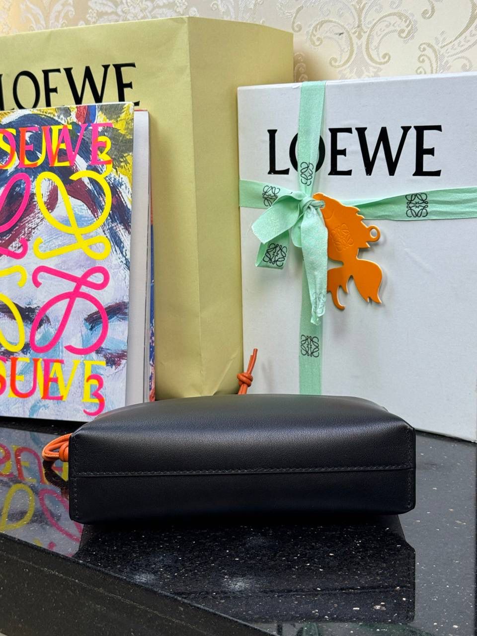 🎈𝘒𝘯𝘰𝘵 𝘛手拿包👜 —【黑色/耀眼橙到货✅】 编码：522414 尺寸：𝟐𝟐.𝟓-𝟓.𝟓-𝟏𝟓.𝟓𝐜𝐦 全新撞色绳结拉链头和腕带设计，顶部拉链开合，内部人字纹帆布衬里以及2个皮隔层卡位，正面饰以品牌标志性烫金𝗟𝗼𝗴𝗼，方便时尚多用。