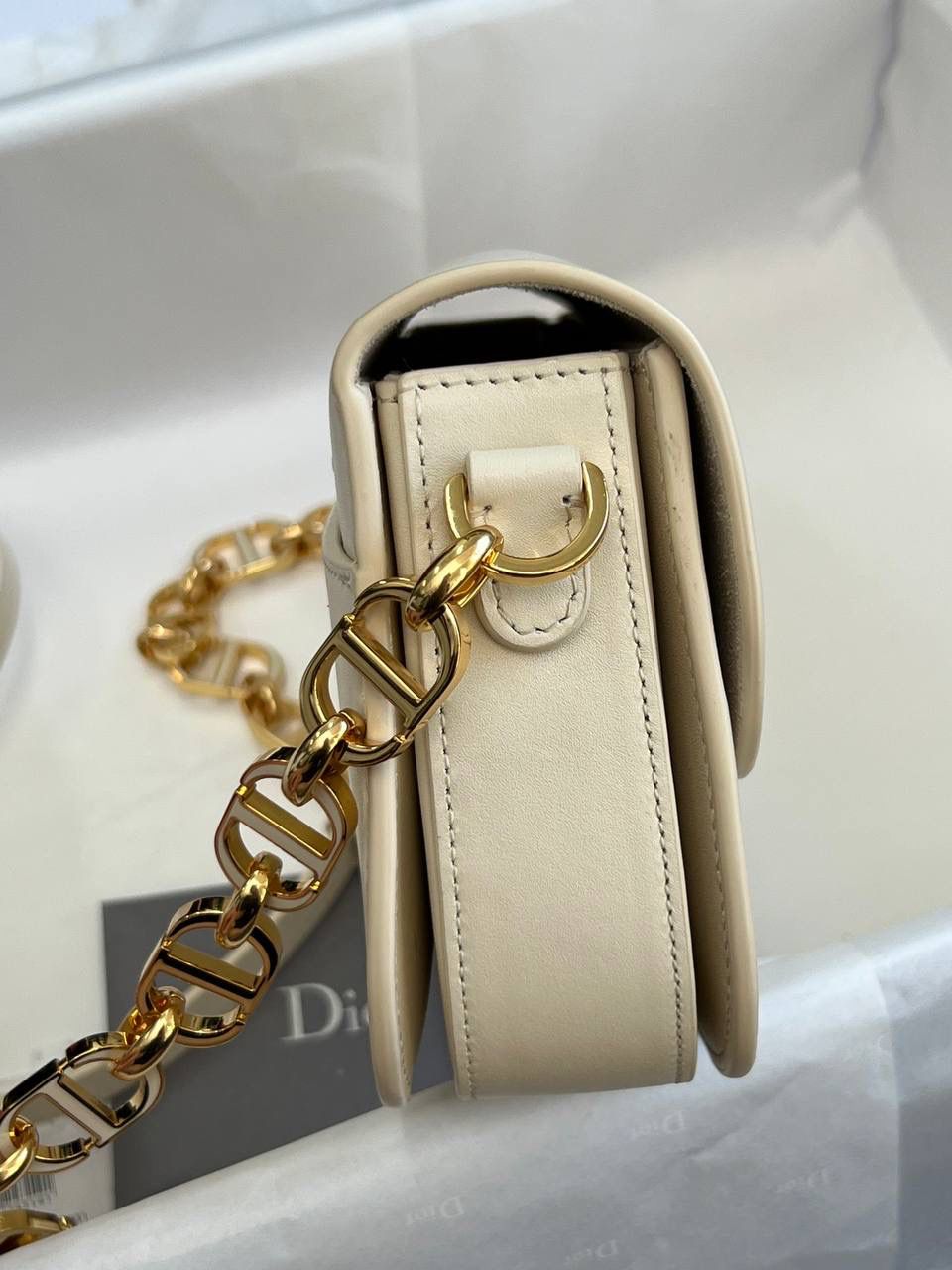 30 MONTAIGNE AVENUE 手袋 灰象牙色光面牛皮革👜✨ 独家渠道货 独家蒙田腋下包白色珐琅扣 尺寸：22.5 x 12.5 x 6.5 厘米 这款 30 Montaigne Avenue 手袋采用典雅的设计，提升此经典系列的格调。 采用黑色光面牛皮革精心制作，圆角翻盖曲线精致，饰以复古金色饰面金属 CD 扣环，灵感源自 Christian Dior 香水瓶的封口。 背面饰以压花 30 Montaigne 标志，搭配由金色饰面金属和与皮革同色调的珐琅链环交替组成的经典链条。 褶层设计，空间宽敞，廓形精致，可手提，肩背或斜挎。