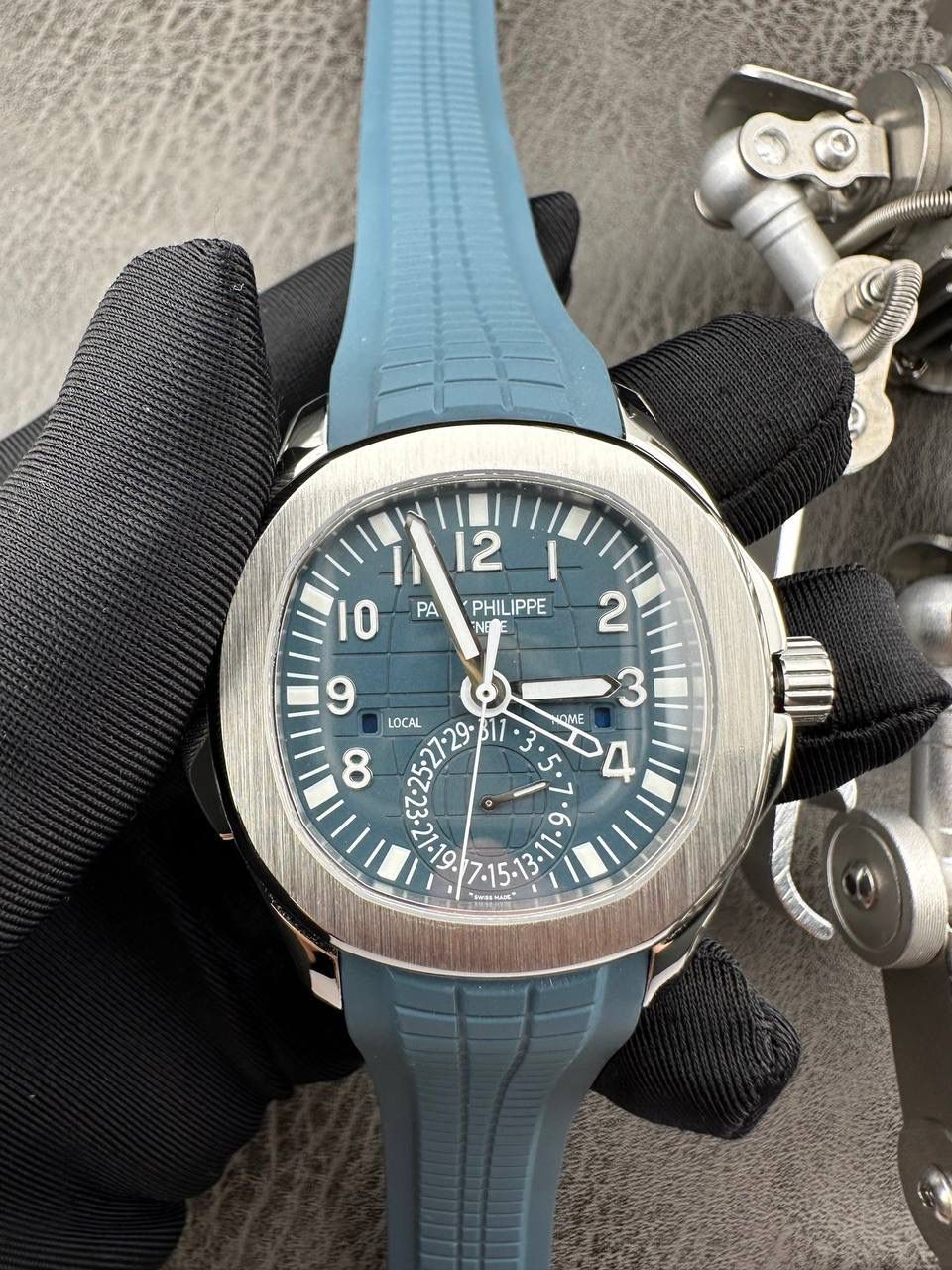 百达翡丽Aquanaut系列😎 【表壳】40.8MM表径，不锈钢材质，圆润的八角壳型恰到好处，表壳左侧的鲨鱼鳍型设计，是可以前后快调中央镂空时针的按钮，这枚指针可以用来指示第二时区时间。 【表盘】黑色浮雕表盘，金属立体字块，覆荧光涂层时标。3、9点钟分别显示”HOME”与”LOCAL”的方形昼夜视窗，蓝白二色各自代表晚上与白天，6点钟位置是指针式的日期盘。 【机芯】成功实现百达翡丽5164A-001内载的324 SC FUS自动上链机芯功能，大三针基础机芯上搭载两地时间模组。 配有休闲气息的Tropical表带，正是为年轻世代所准备的奢华运动表。