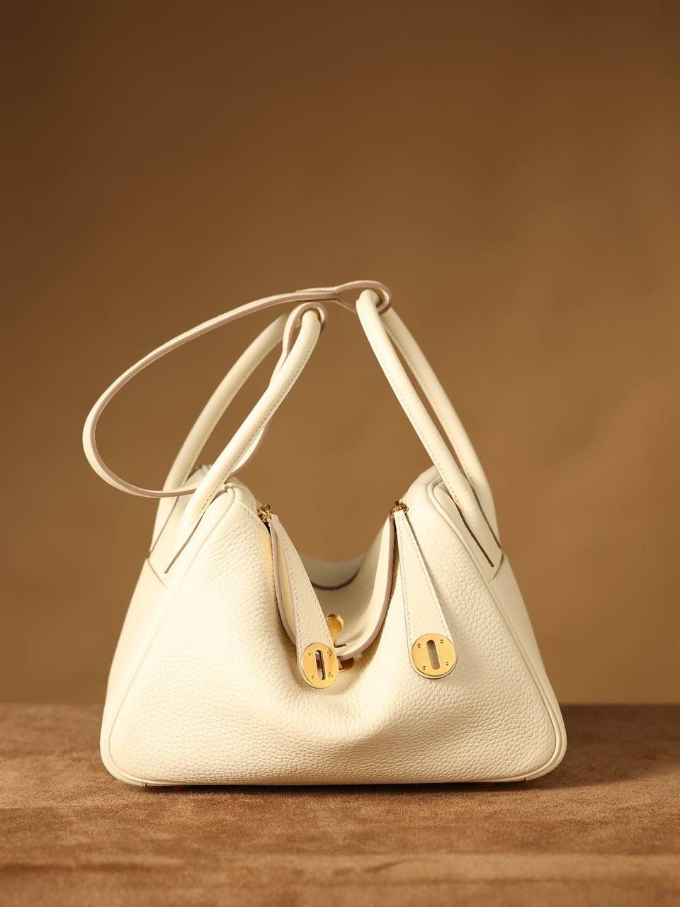 Hermes 爱马仕 Lindy 26cm 奶油白金扣👜✨ 尺寸：26*18*14 cm 奶油白真的实物很漂亮，YYDS😍 五金介绍，拉链尾部的"H"是刚好的正方形，而且每笔都是很直，菱角分明，表明平整 图二至六图的的五金四个小螺丝是人工围着这四个小圆点边雕琢上去的，而且小螺丝这点的周围圈是有孤独深的圆形，这点很多人都不知道，这个是符合正品工艺的 拉链是纯原装金扣的RIRI拉链 所以在五金方面我们拿捏的死死的 无人能敌 🤟🏻 渠道货是注重任何一个细节的 做到任何人都做不到的点 这就是天花板😍💯👍