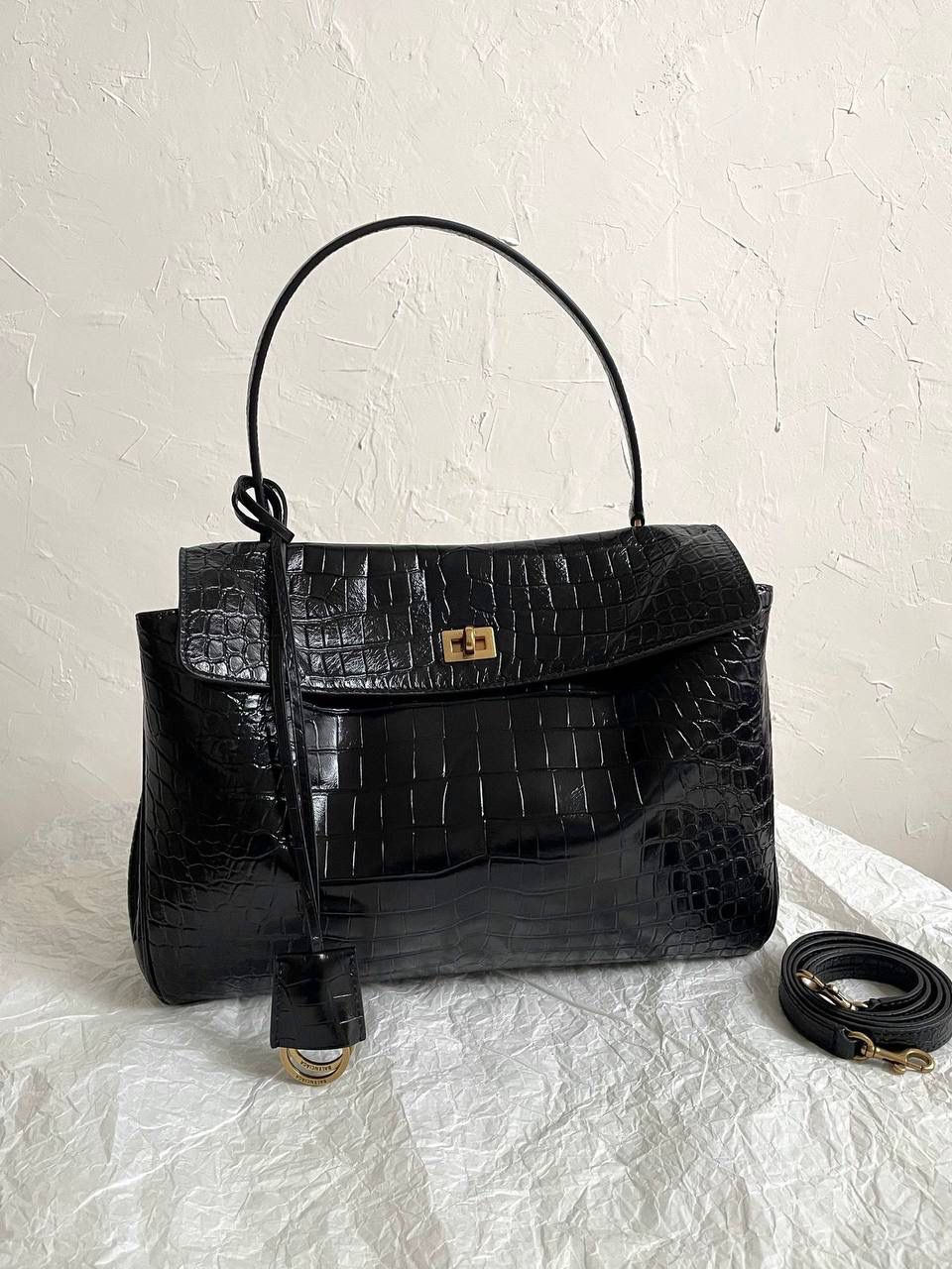 ba1enciaga rodeo 鳄鱼纹黑金中号🕋 纯纯的大爆款，大家都知道吧 一到冬天就想要整点油亮亮的包来点缀 但是又不想买饱和度过高的颜色 百搭还是基本的诉求嘛 所以这只亮面牛皮鳄鱼压纹rodeo就是很好的选择！ 鳄鱼纹压纹最怕皮硬 一定要够软包型才够慵懒 我们是自家定制皮料，非市场通货❌ 我们是不会跟风用通货皮做的😡 mini真心可爱，和kelly20的大耳朵很像很像 大号：39.8×29.9×12.9cm789744m 中号：35×23.3×10.9cm789772m 小号：28.9×20×9.9cm789779m mini：23×17×9cm795456m