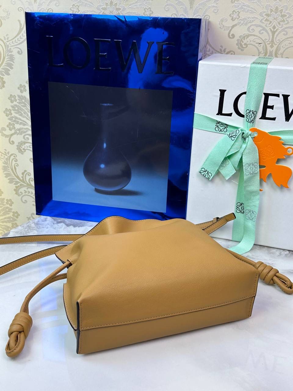 Flamenco clutch ✦迷你✦ 尺寸：𝟐𝟐.𝟓-𝟏𝟖-𝟗𝐜𝐦 型号：052030 棕色 ❤️mini flamenco clutch bag 可手拿亦可优雅斜挎 云朵般温暖亦轻盈的造型如此简单，💯耐看💯不会out的款式！ ❤️包袋采用进口小牛皮，手感如羊皮般细腻柔软，却比羊皮更加结实耐用，麂皮内衬 ❤️品牌标志性绳结设计，收紧袋口就是小福袋造型，超Q，看着不大实际超会装😇