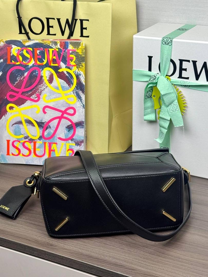 🎈【周年限定】 小号纳帕羊皮𝗙𝗲𝗮𝘁𝗵𝗲𝗿𝗹𝗶𝗴𝗵𝘁 𝗣𝘂𝘇𝘇𝗹𝗲手袋👜 ——黑色到货❤️ 尺寸：𝟮𝟰-𝟭𝟬.𝟱-𝟭𝟲.𝟱𝗰𝗺 编码：061610【配全套礼盒】 ✅延续经典老款𝗣𝘂𝘇𝘇𝗹𝗲做法，全新𝗣𝘂𝘇𝘇𝗹𝗲内外采用柔软轻盈的纳帕羊皮材质，为手袋注入随性慵懒的风格。 ✅该款饰有旋转卡扣，铰链式拉链头，一个外部拉链后袋，一个内部插袋，以及可拆卸式的𝗟𝗢𝗘𝗪𝗘烫金或烫银标签，饰有隐秘口袋和气球骰子，底部长方形金属脚钉。搭配可拆卸可调节长肩带，可肩背、斜挎或手提。