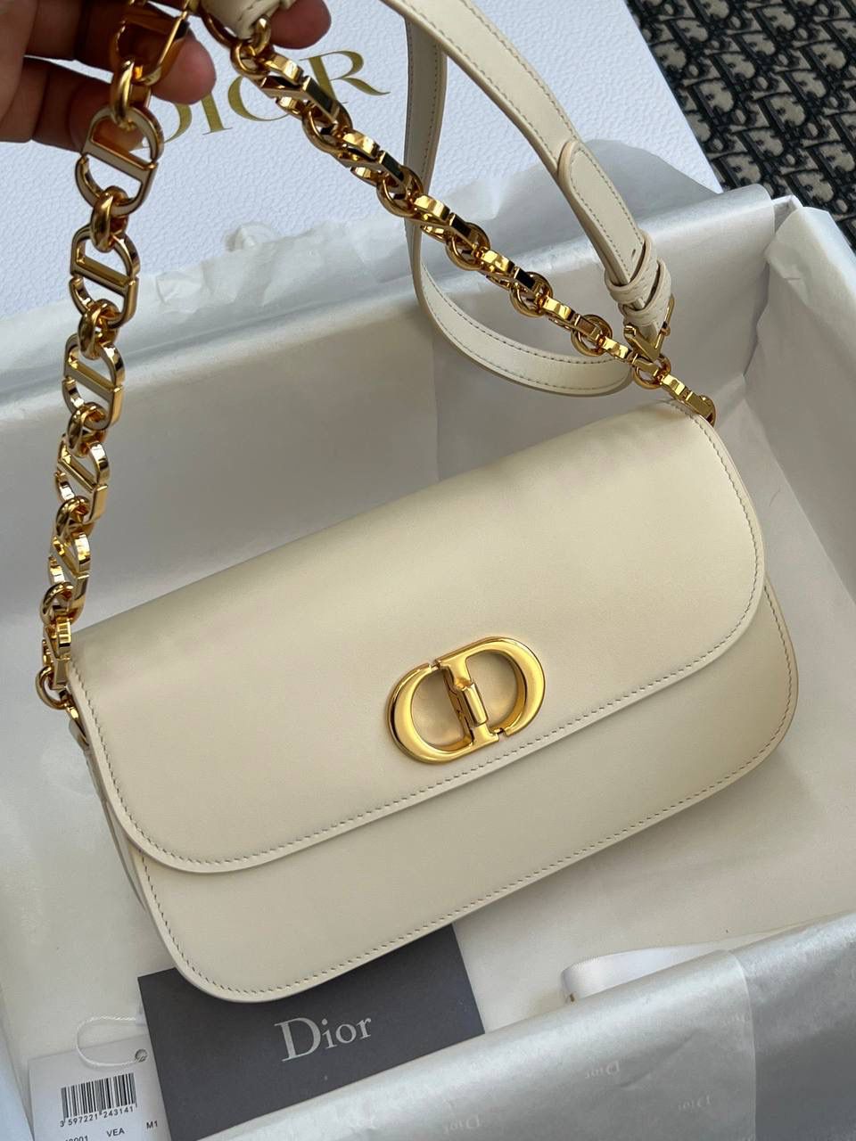 30 MONTAIGNE AVENUE 手袋 灰象牙色光面牛皮革👜✨ 独家渠道货 独家蒙田腋下包白色珐琅扣 尺寸：22.5 x 12.5 x 6.5 厘米 这款 30 Montaigne Avenue 手袋采用典雅的设计，提升此经典系列的格调。 采用黑色光面牛皮革精心制作，圆角翻盖曲线精致，饰以复古金色饰面金属 CD 扣环，灵感源自 Christian Dior 香水瓶的封口。 背面饰以压花 30 Montaigne 标志，搭配由金色饰面金属和与皮革同色调的珐琅链环交替组成的经典链条。 褶层设计，空间宽敞，廓形精致，可手提，肩背或斜挎。