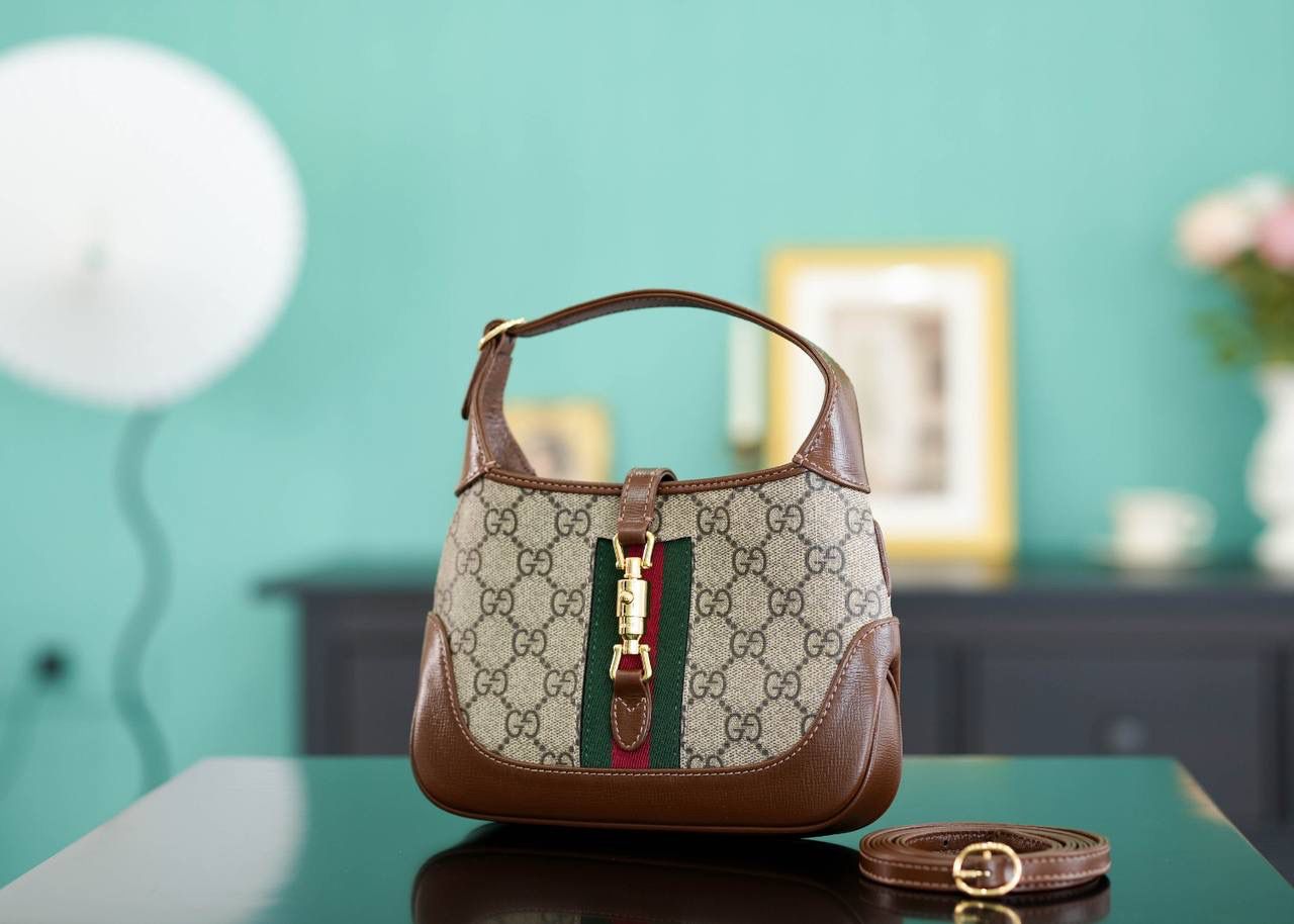 🥯GG Jackie 1961系列迷你手袋 棕色19cm 正品售价,500 经典𝙅𝙖𝙘𝙠𝙞𝙚是爱豆们最近的心头好 mini可爱程度超出我的想像 绿红织带复古设计 将60年代的气息与现代的时尚融合交汇 不仅让人感受到浓郁的复古美感， 还多了时尚潮流的气息，结合起来真的是非常赞！！！ 两条肩带设计，腋下背单肩背多风格背法~ 官方款号 637092 尺寸：19x13x3cm