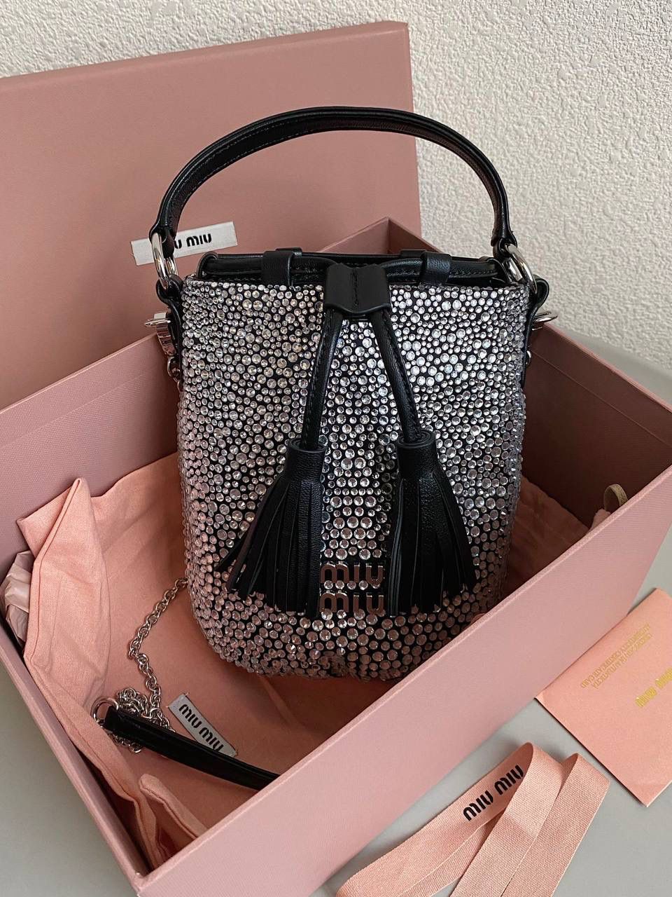 🈶钻石黑 𝗠𝗶𝘂𝗠𝗶𝘂满钻水桶包 blingbling的又是多少女生的心头爱 整个包身贴满水晶，搭配软绵绵的小羊皮， 在光线下非常闪✨不管是日常约会， 节日派对 晚宴都会是人群中的抢眼包 15×17×11cm F0053m