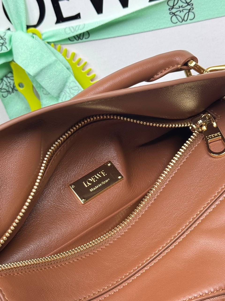 🎈【周年限定】 小号纳帕羊皮𝗙𝗲𝗮𝘁𝗵𝗲𝗿𝗹𝗶𝗴𝗵𝘁 𝗣𝘂𝘇𝘇𝗹𝗲手袋👜 ——山核桃色到货❤️ 尺寸：𝟮𝟰-𝟭𝟬.𝟱-𝟭𝟲.𝟱𝗰𝗺 编码：061610【配全套礼盒】 ✅延续经典老款𝗣𝘂𝘇𝘇𝗹𝗲做法，全新𝗣𝘂𝘇𝘇𝗹𝗲内外采用柔软轻盈的纳帕羊皮材质，为手袋注入随性慵懒的风格。 ✅该款饰有旋转卡扣，铰链式拉链头，一个外部拉链后袋，一个内部插袋，以及可拆卸式的𝗟𝗢𝗘𝗪𝗘烫金或烫银标签，饰有隐秘口袋和气球骰子，底部长方形金属脚钉。搭配可拆卸可调节长肩带，可肩背、斜挎或手提。