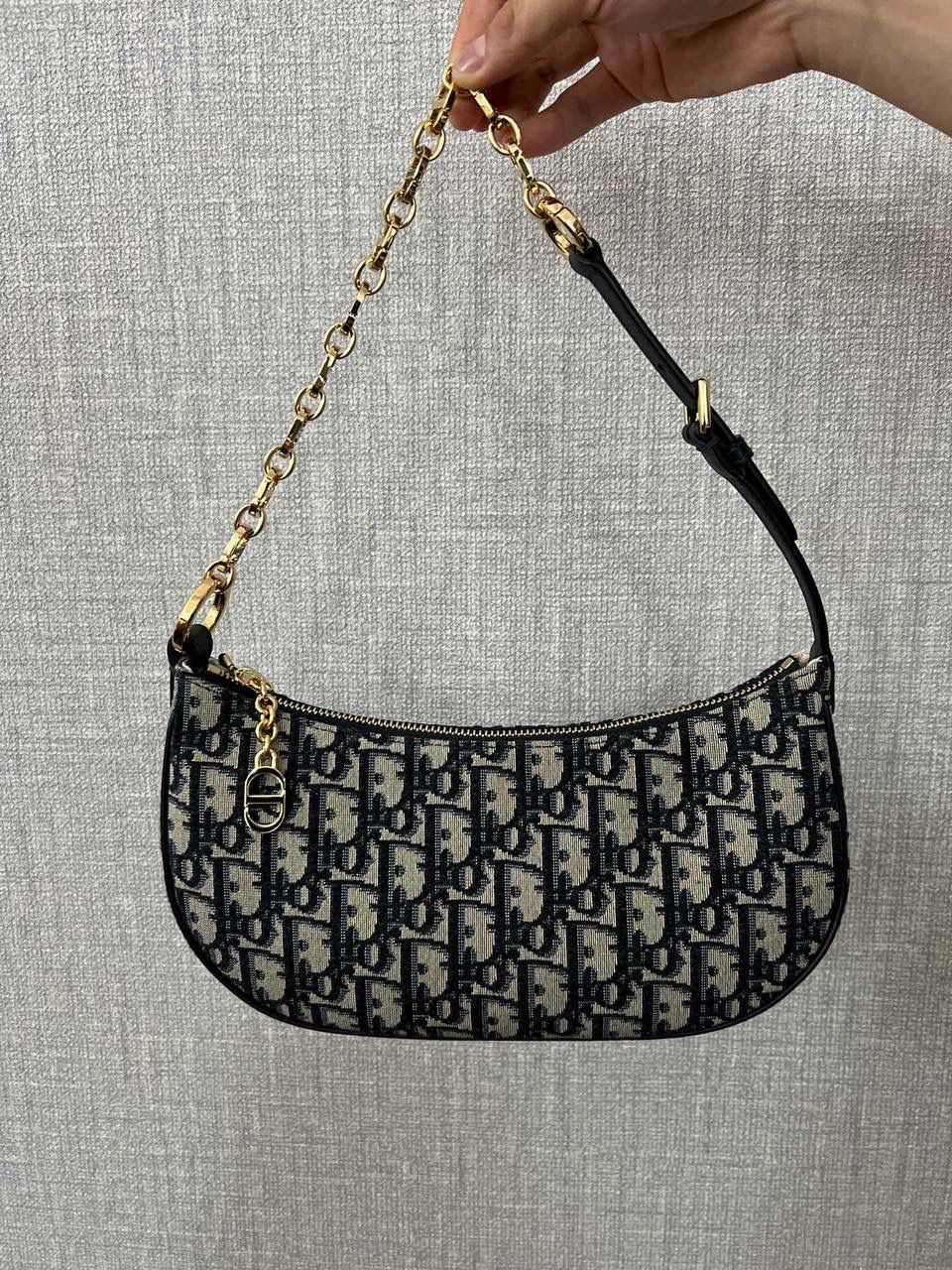 CD LOUNGE 手袋蓝色 Oblique 印花👜✨ 独家渠道货 独家腋下包老花 尺寸：26 x 15 x 5.5 厘米 这款 CD Lounge 手袋是2023夏季新品，彰显 Dior 的现代审美与高订风范。 采用蓝色 Oblique 印花面料精心制作，突显 Dior 经典图案。 经典链条与皮革搭配，交替饰以金色饰面金属和同色调珐琅链环，可折叠设计，可肩背或手提。 拉链开合搭配 CD 拉链头 可调节肩带，链条部分由金色饰面金属和与皮革同色调的珐琅 CD 链环组成，搭配皮革带 内含防尘袋