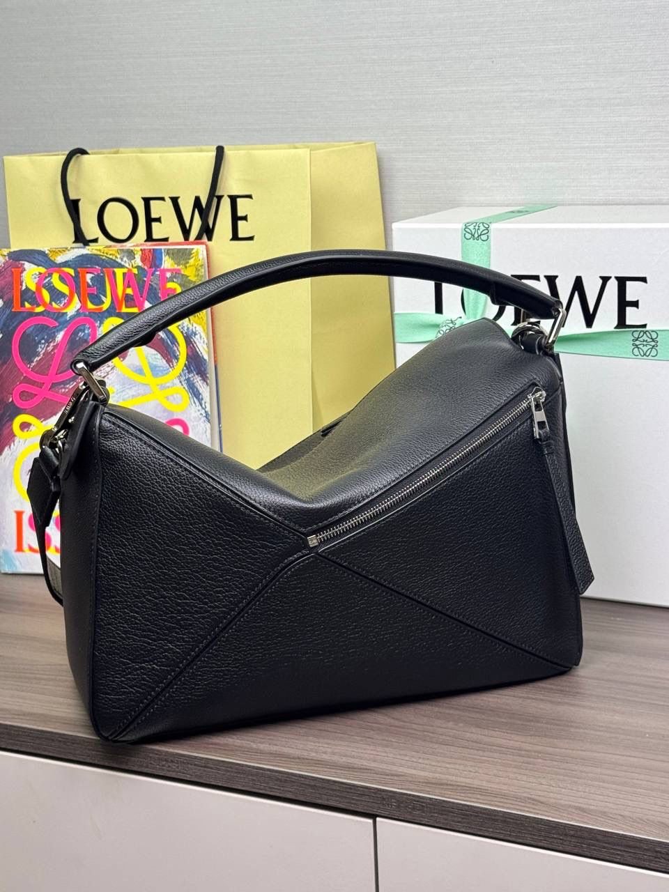 🎈【全钢】大号鹿皮𝘗𝘶𝘻𝘻𝘭𝘦* ——【👉🏻黑色到货✅】 尺寸：𝟑𝟐.𝟓-𝟏𝟒.𝟓-𝟐𝟑.𝟓𝐜𝐦 编码：260403 【配全套包装】 ❤️经典拼图系列•不规则立体几何设计•最具辨识度的立体廓形和几何美学•顶级进口皮搭配德国沙菲线•独家定制五金•𝗬𝗞𝗞拉链拉头。 ❤️该款大号采用鹿皮革制成•绒面内里•搭配一条可拆卸可调节的皮肩带•肩背斜挎或手提多样化背法。