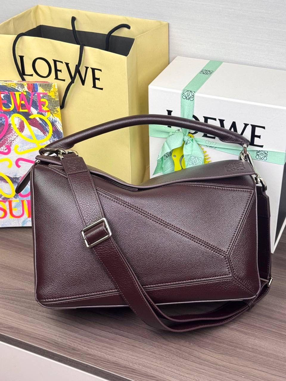 🎈【全钢】大号鹿皮𝘗𝘶𝘻𝘻𝘭𝘦* ——【👉🏻牛血色到货✅】 尺寸：𝟑𝟐.𝟓-𝟏𝟒.𝟓-𝟐𝟑.𝟓𝐜𝐦 编码：260403 【配全套包装】 ❤️经典拼图系列•不规则立体几何设计•最具辨识度的立体廓形和几何美学•顶级进口皮搭配德国沙菲线•独家定制五金•𝗬𝗞𝗞拉链拉头。 ❤️该款大号采用鹿皮革制成•绒面内里•搭配一条可拆卸可调节的皮肩带•肩背斜挎或手提多样化背法。