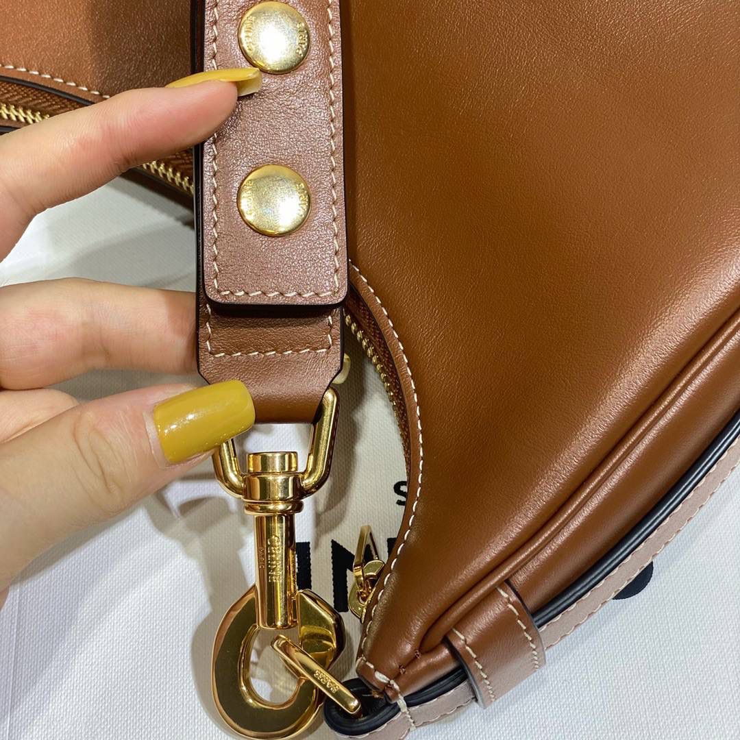 🔥大货实拍图 𝗖𝗘𝗟𝗜𝗡𝗘 ♥ 𝗔𝗩𝗔 𝗦𝗧𝗥𝗔𝗣 独特新月包型打造摩登格调，醒目金属圆环与考究皮革饰带点缀，匠心与巧思交织，定格别致意趣造型。型号：196923 尺寸：24*13*7cm