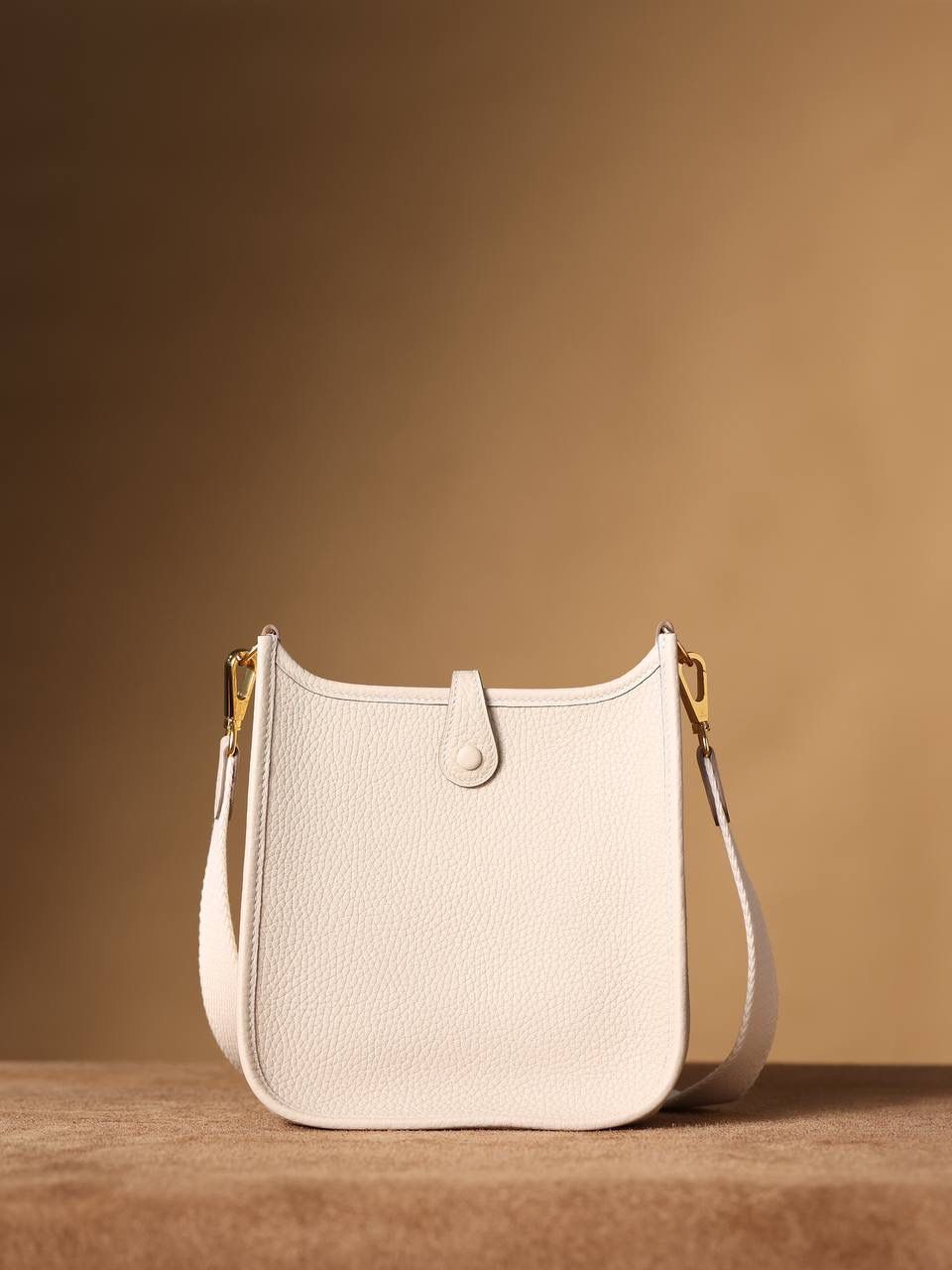 HERMES爱马仕Evelyne 16伊芙琳奶昔白金扣👜✨ TaurillonMaurice 小公牛皮 尺寸：16*18*5cm 爱马仕Evelyne伊芙琳 Evelyne包的设计灵感来自于一种名为“马鞍袋”的马具袋，这是一种常用于骑手和马车夫的袋子，用于储存和运输马具和其他必需品。 爱马仕将这种马具袋的经典元素与品牌的手工艺传统相结合，打造出了具有时尚感和功能性的包包。 因此，伊芙琳包不仅是一款实用的手提包，同时也代表着品牌深厚的历史和文化传统❤️