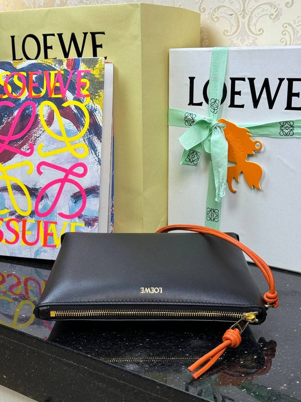 🎈𝘒𝘯𝘰𝘵 𝘛手拿包👜 —【黑色/耀眼橙到货✅】 编码：522414 尺寸：𝟐𝟐.𝟓-𝟓.𝟓-𝟏𝟓.𝟓𝐜𝐦 全新撞色绳结拉链头和腕带设计，顶部拉链开合，内部人字纹帆布衬里以及2个皮隔层卡位，正面饰以品牌标志性烫金𝗟𝗼𝗴𝗼，方便时尚多用。