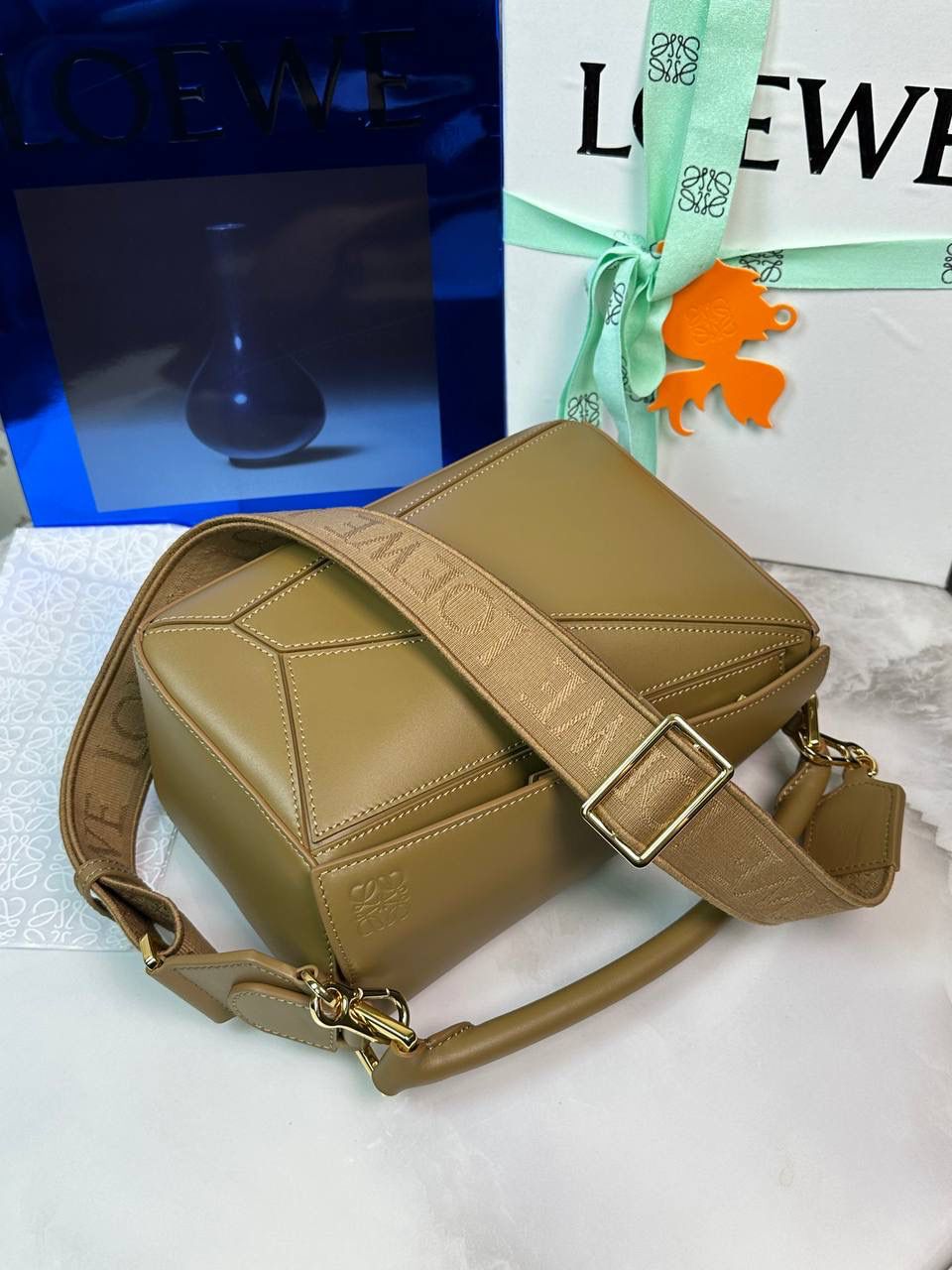 🅰️小号 𝗣𝘂𝘇𝘇𝗹𝗲最新版本❤️ ——（缎面/织带款） ✅经典拼图系列，不规则立体几何设计，最具辨识度的立体廓形和几何美学，顶级进口小牛皮搭配德国沙菲线，独家定制五金，𝗬𝗞𝗞拉链拉头 ✅容量超大，颜值高，四季百搭，新款自带可拆卸𝗟𝗢𝗘𝗪𝗘织带宽肩带‼️ 尺寸：𝟐𝟒-𝟏𝟎.𝟓-𝟏𝟔.𝟓𝐜𝐦 款号：061609织带款橡木棕