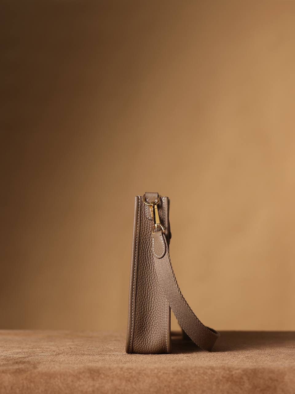 HERMES爱马仕Evelyne 16伊芙琳大象灰金扣👜✨ TaurillonMaurice 小公牛皮 尺寸：16*18*5cm 爱马仕Evelyne伊芙琳 Evelyne包的设计灵感来自于一种名为“马鞍袋”的马具袋，这是一种常用于骑手和马车夫的袋子，用于储存和运输马具和其他必需品。 爱马仕将这种马具袋的经典元素与品牌的手工艺传统相结合，打造出了具有时尚感和功能性的包包。 因此，伊芙琳包不仅是一款实用的手提包，同时也代表着品牌深厚的历史和文化传统❤️