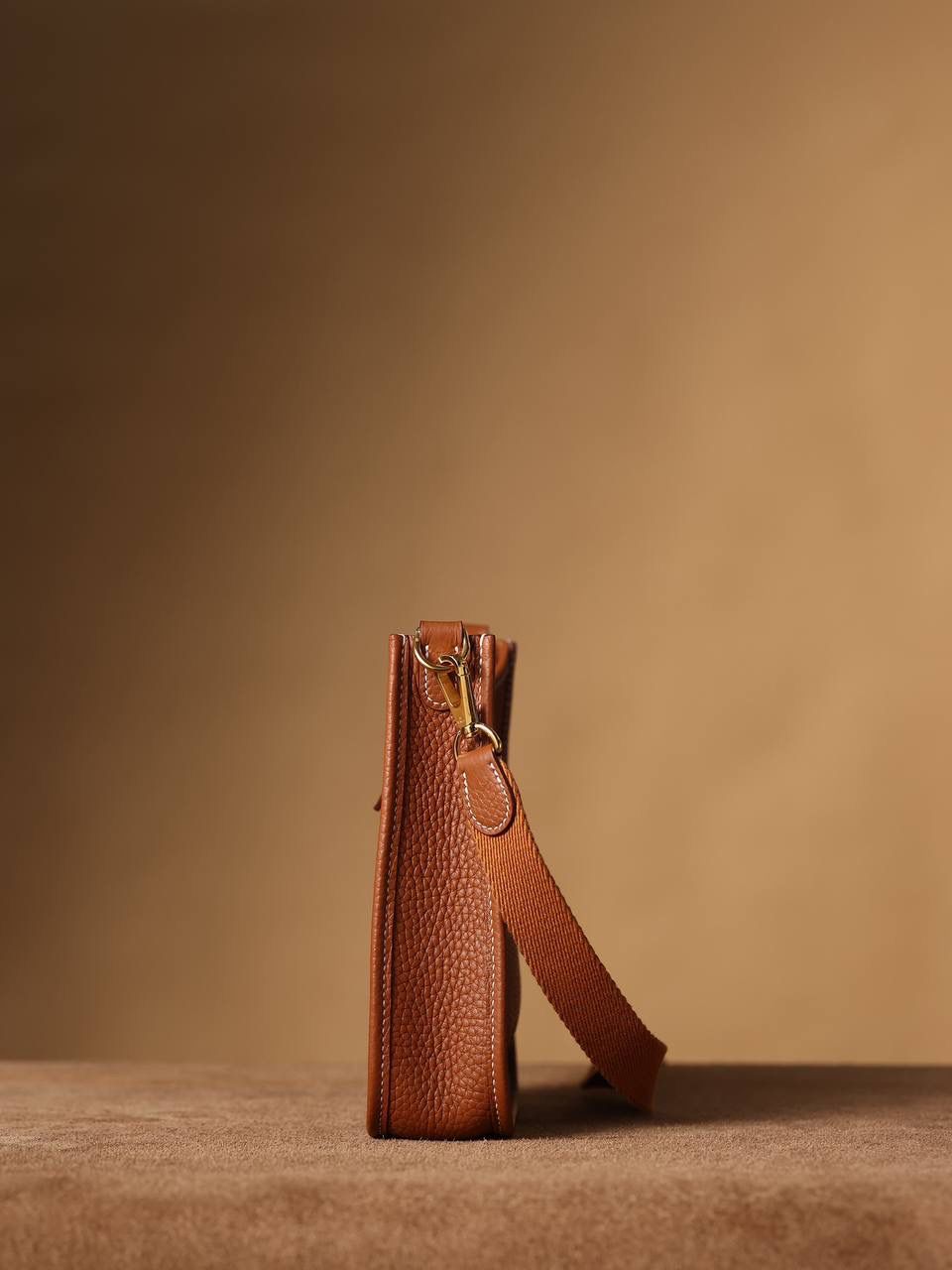 HERMES爱马仕Evelyne 16伊芙琳金棕金扣👜✨ TaurillonMaurice 小公牛皮 尺寸：16*18*5cm 爱马仕Evelyne伊芙琳 Evelyne包的设计灵感来自于一种名为“马鞍袋”的马具袋，这是一种常用于骑手和马车夫的袋子，用于储存和运输马具和其他必需品。 爱马仕将这种马具袋的经典元素与品牌的手工艺传统相结合，打造出了具有时尚感和功能性的包包。 因此，伊芙琳包不仅是一款实用的手提包，同时也代表着品牌深厚的历史和文化传统❤️