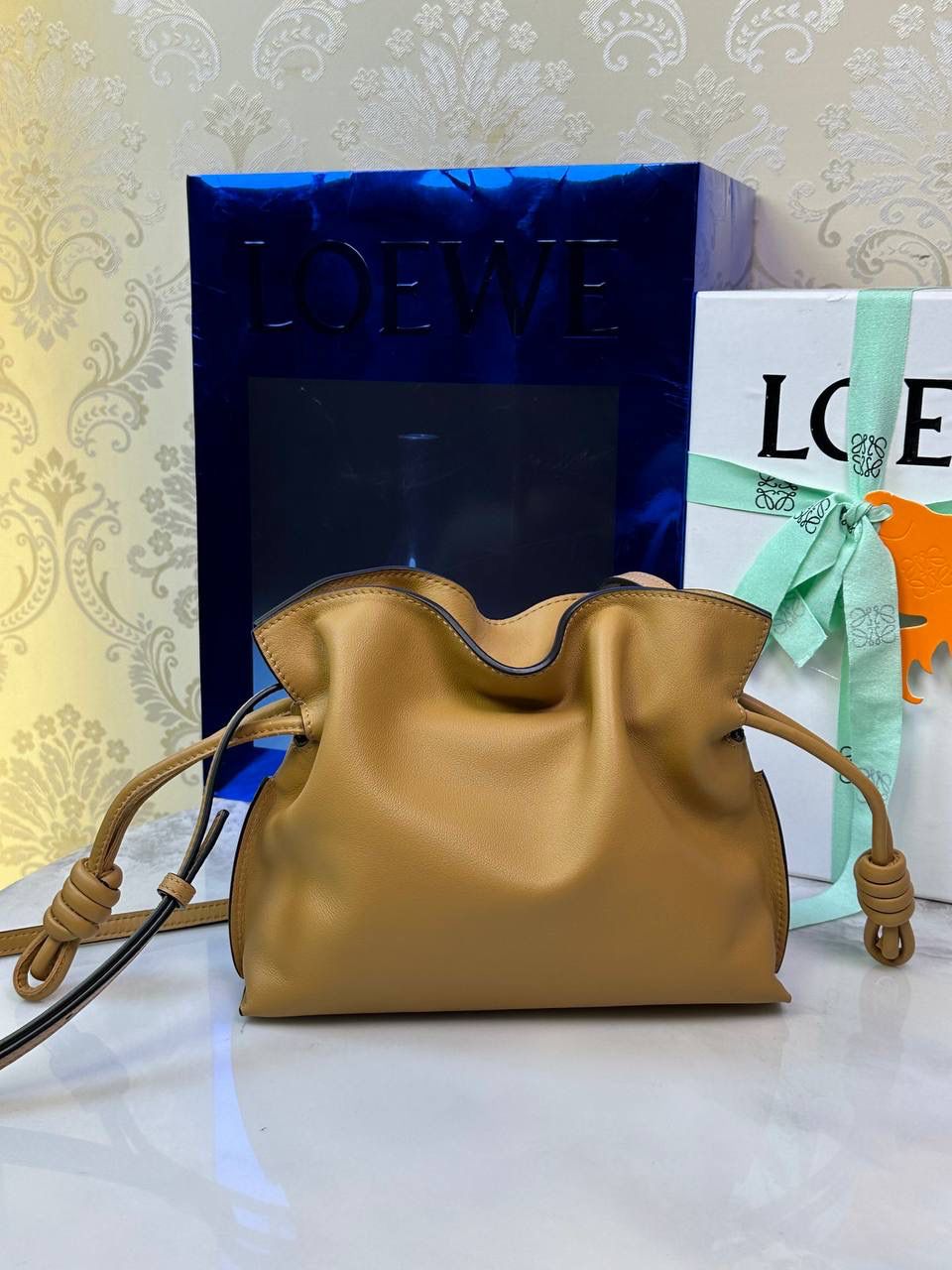 Flamenco clutch ✦迷你✦ 尺寸：𝟐𝟐.𝟓-𝟏𝟖-𝟗𝐜𝐦 型号：052030 棕色 ❤️mini flamenco clutch bag 可手拿亦可优雅斜挎 云朵般温暖亦轻盈的造型如此简单，💯耐看💯不会out的款式！ ❤️包袋采用进口小牛皮，手感如羊皮般细腻柔软，却比羊皮更加结实耐用，麂皮内衬 ❤️品牌标志性绳结设计，收紧袋口就是小福袋造型，超Q，看着不大实际超会装😇