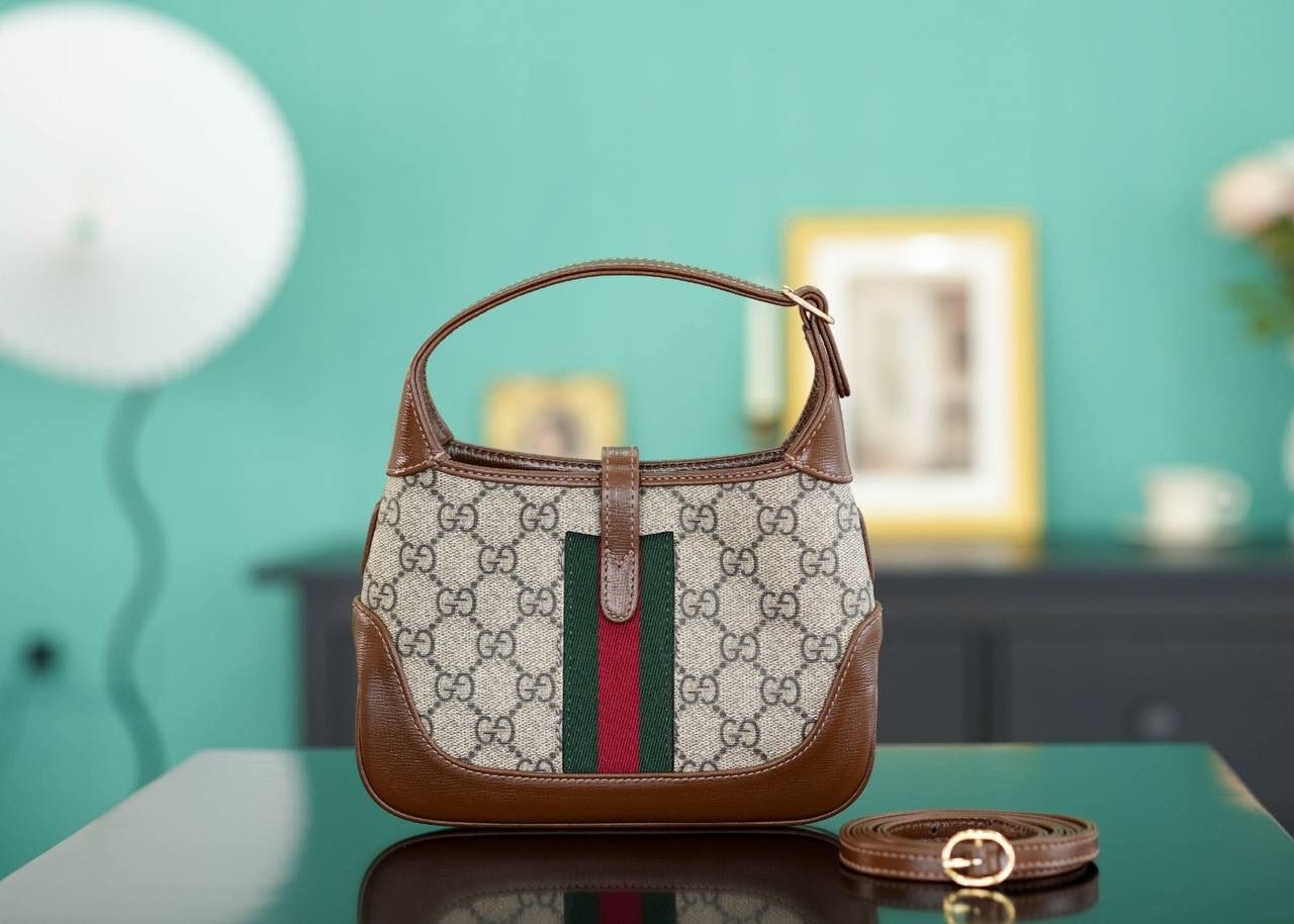 🥯GG Jackie 1961系列迷你手袋 棕色19cm 正品售价,500 经典𝙅𝙖𝙘𝙠𝙞𝙚是爱豆们最近的心头好 mini可爱程度超出我的想像 绿红织带复古设计 将60年代的气息与现代的时尚融合交汇 不仅让人感受到浓郁的复古美感， 还多了时尚潮流的气息，结合起来真的是非常赞！！！ 两条肩带设计，腋下背单肩背多风格背法~ 官方款号 637092 尺寸：19x13x3cm