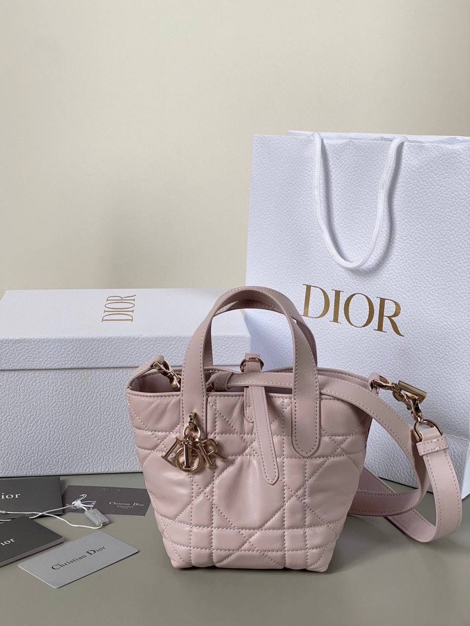 🈶粉色，迷你 𝗗𝗜𝗢𝗥 𝗧𝗼𝘂𝗷𝗼𝘂𝗿𝘀新版竖款 火爆全网toujours缩小版来啦！ 看到真的心动得不行～ 实物就是常规迷你水桶大小， 真的可爱死 别说，包虽小但容量还挺大的 日常用品都能轻松装上 肩带长度也刚刚好，不挑身高 反正就是太乖啦！夏日必备 😍 13×15×12cm #M1272m