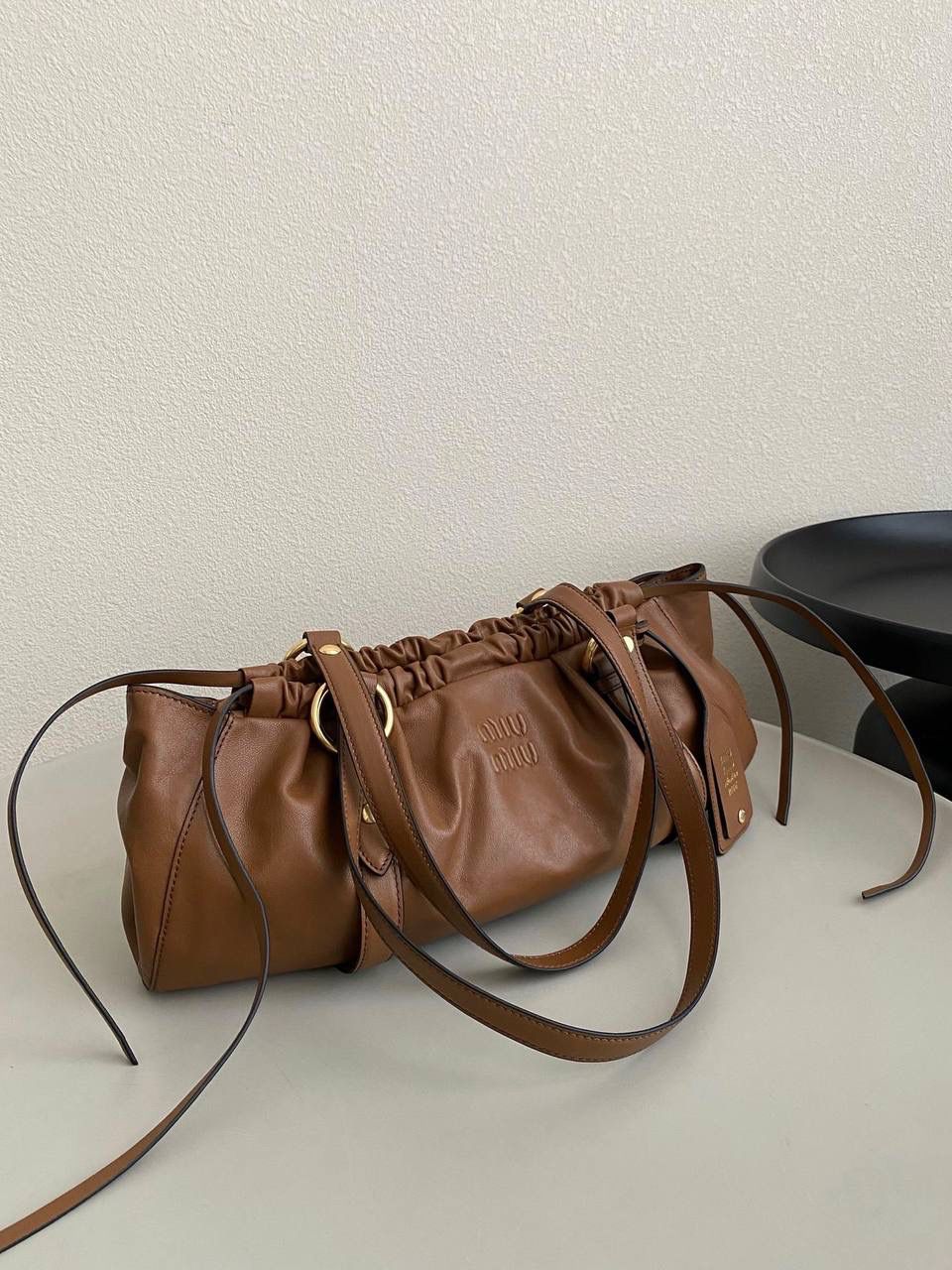 🈶焦糖色 𝗠𝗶𝘂𝗠𝗶𝘂 𝗡𝗮𝗽𝗽𝗮 饺子包 这只亮点在于包口用的是抽绳束口！ 抽绳可以随意调节，搭配的纤长双手柄可肩背或手提也可以随意捧在腰际'柔软的皮质加上不定型的设计，慵懒随性的调调一下就出来了 满满的vintgge复古感，既叛逆又不失格调'好喜欢啊 16×44×10.5cm #F0016m