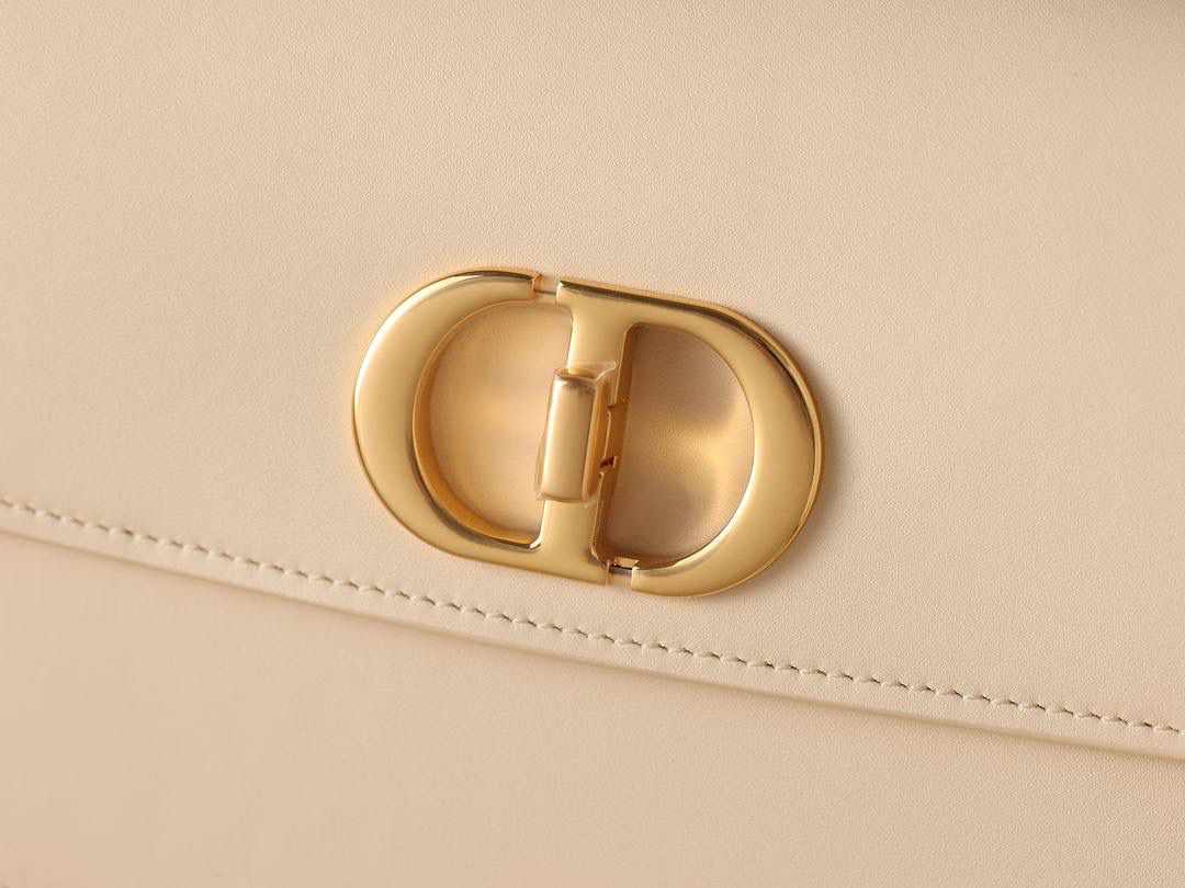 30 MONTAIGNE AVENUE 手袋 灰象牙色光面牛皮革👜✨ 独家渠道货 独家蒙田腋下包白色珐琅扣 尺寸：22.5 x 12.5 x 6.5 厘米 这款 30 Montaigne Avenue 手袋采用典雅的设计，提升此经典系列的格调。 采用黑色光面牛皮革精心制作，圆角翻盖曲线精致，饰以复古金色饰面金属 CD 扣环，灵感源自 Christian Dior 香水瓶的封口。 背面饰以压花 30 Montaigne 标志，搭配由金色饰面金属和与皮革同色调的珐琅链环交替组成的经典链条。 褶层设计，空间宽敞，廓形精致，可手提，肩背或斜挎。