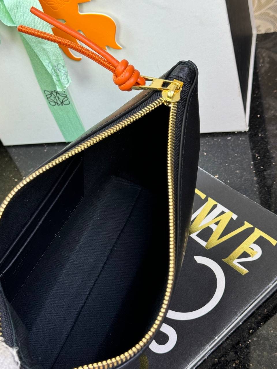 🎈𝘒𝘯𝘰𝘵 𝘛手拿包👜 —【黑色/耀眼橙到货✅】 编码：522414 尺寸：𝟐𝟐.𝟓-𝟓.𝟓-𝟏𝟓.𝟓𝐜𝐦 全新撞色绳结拉链头和腕带设计，顶部拉链开合，内部人字纹帆布衬里以及2个皮隔层卡位，正面饰以品牌标志性烫金𝗟𝗼𝗴𝗼，方便时尚多用。