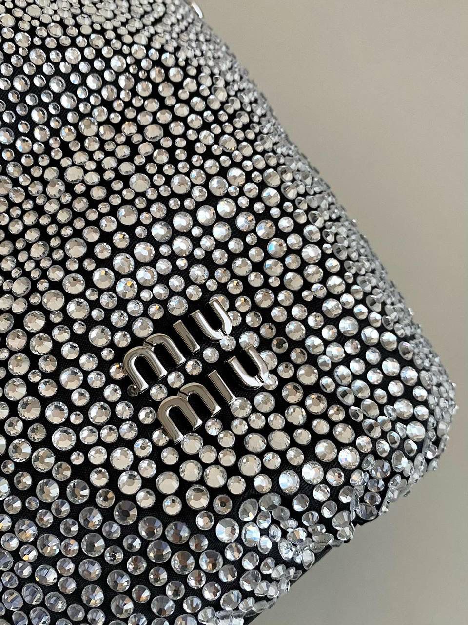 🈶钻石黑 𝗠𝗶𝘂𝗠𝗶𝘂满钻水桶包 blingbling的又是多少女生的心头爱 整个包身贴满水晶，搭配软绵绵的小羊皮， 在光线下非常闪✨不管是日常约会， 节日派对 晚宴都会是人群中的抢眼包 15×17×11cm F0053m