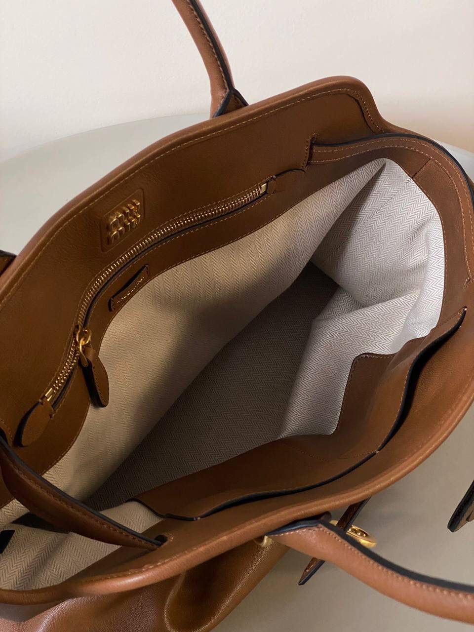 🈶焦糖色， 𝗠𝗶𝘂𝗠𝗶𝘂 手提包 这只Aventure我要夸爆它！ 绝对是公文包中的颜值天花板 这款有多难买不用多说，绝对的断货王 酷酷的慵懒感洋气且时髦 还有一丢vintage感，超有调 上班通勤，日常出街都超出片 很有年轻人的活力！ 31×40×13cm #F0023m