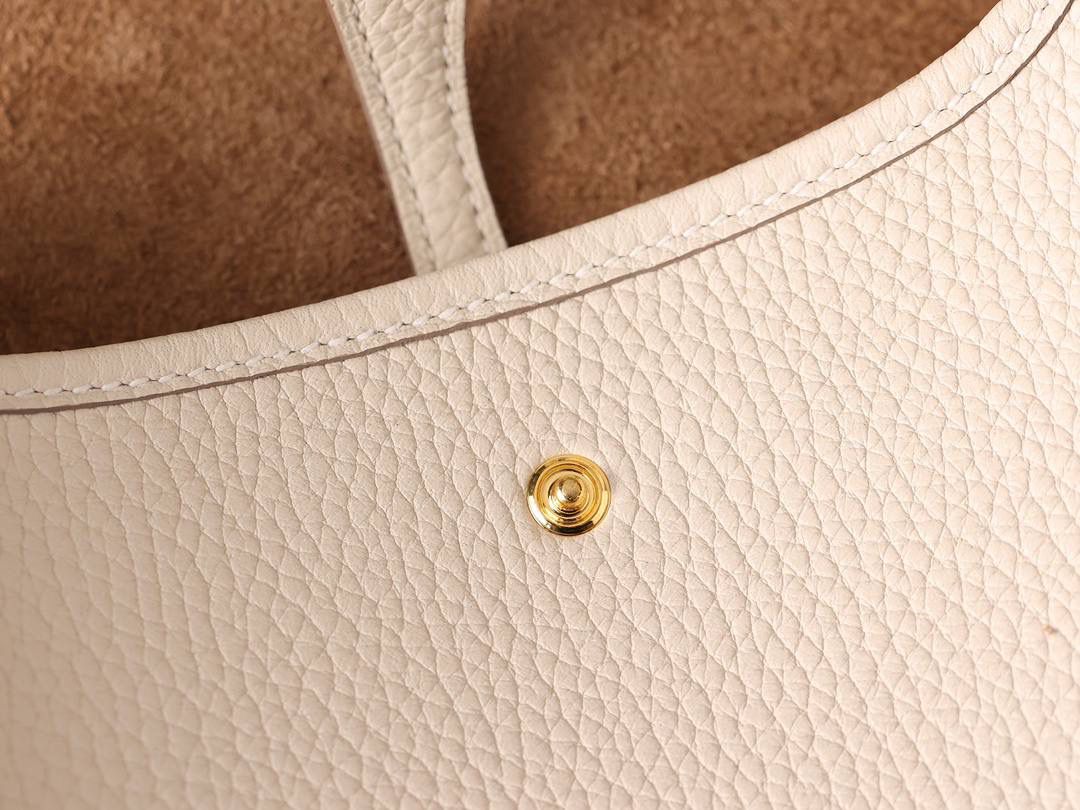 HERMES爱马仕Evelyne 16伊芙琳奶昔白金扣👜✨ TaurillonMaurice 小公牛皮 尺寸：16*18*5cm 爱马仕Evelyne伊芙琳 Evelyne包的设计灵感来自于一种名为“马鞍袋”的马具袋，这是一种常用于骑手和马车夫的袋子，用于储存和运输马具和其他必需品。 爱马仕将这种马具袋的经典元素与品牌的手工艺传统相结合，打造出了具有时尚感和功能性的包包。 因此，伊芙琳包不仅是一款实用的手提包，同时也代表着品牌深厚的历史和文化传统❤️