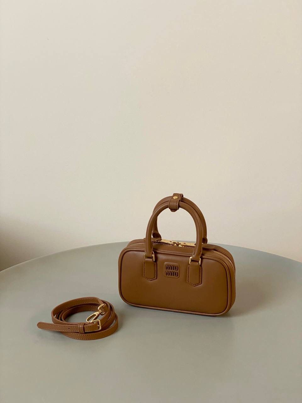 🈶干邑色，迷你 𝗠𝗶𝘂𝗠𝗶𝘂保龄球，大爆款 新尺寸也太可爱了！ 喜欢小包的姐妹这只必买！它要比小号小一些也窄一些 就巴掌大小，但容量还挺大的 装俩部手机都绰绰有余，日常够用 肩带长短也很ok，手拎斜挎都好看 反正放心冲就是了！拥有它，上班牛马的心情都会被治愈～ 迷你：19×10×5cm #F0011m 小号：22x10.5x7.5cm 大号：27x12x9cm