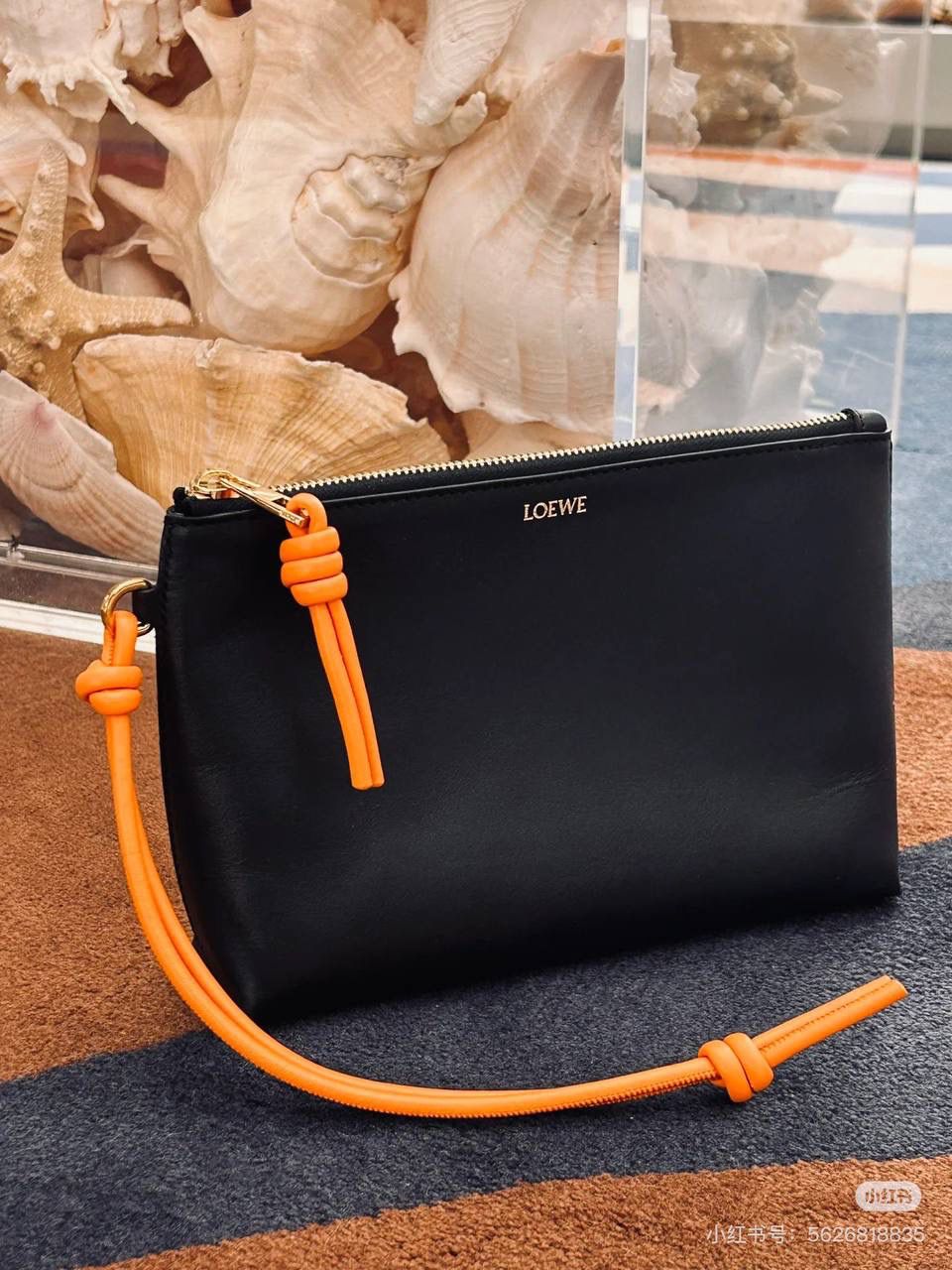 🎈𝘒𝘯𝘰𝘵 𝘛手拿包👜 —【黑色/耀眼橙到货✅】 编码：522414 尺寸：𝟐𝟐.𝟓-𝟓.𝟓-𝟏𝟓.𝟓𝐜𝐦 全新撞色绳结拉链头和腕带设计，顶部拉链开合，内部人字纹帆布衬里以及2个皮隔层卡位，正面饰以品牌标志性烫金𝗟𝗼𝗴𝗼，方便时尚多用。