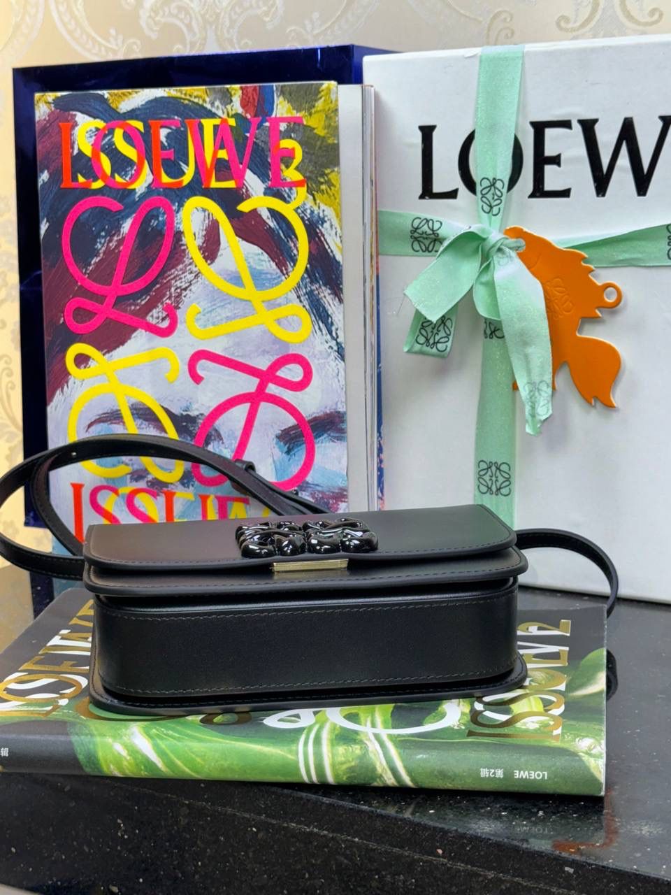 🎈单色釉𝘎𝘰𝘺𝘢*缎面皮 —【黑色到货✅】 尺寸：𝟏𝟗-𝟔-𝟏𝟑.𝟓𝐜𝐦 编码：262123 【配全套礼盒】 ✅汲取古代单色釉瓷器色彩灵感，全新打造𝘓𝘰𝘸𝘦*单色釉系列。该款采用缎面丝绸牛皮搭配内里纳帕羊皮，手感丝滑细腻。正面立体膨胀𝘈𝘯𝘨𝘳𝘢𝘮 𝘓𝘰𝘨𝘰设计搭配陶瓷小兔子挂饰，堪称时尚界的艺术品。 ✅磁扣开合，内部3个隔层设计，以及按扣和背面小侧袋，收纳方便➕安全感满分，能装，好搭。