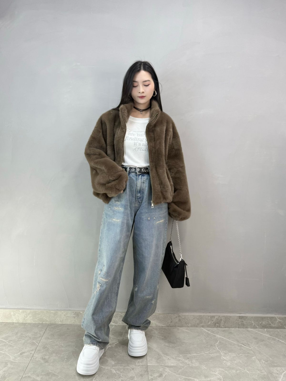 Woman in brown fur coat with sweatshirt jeans and sneakers