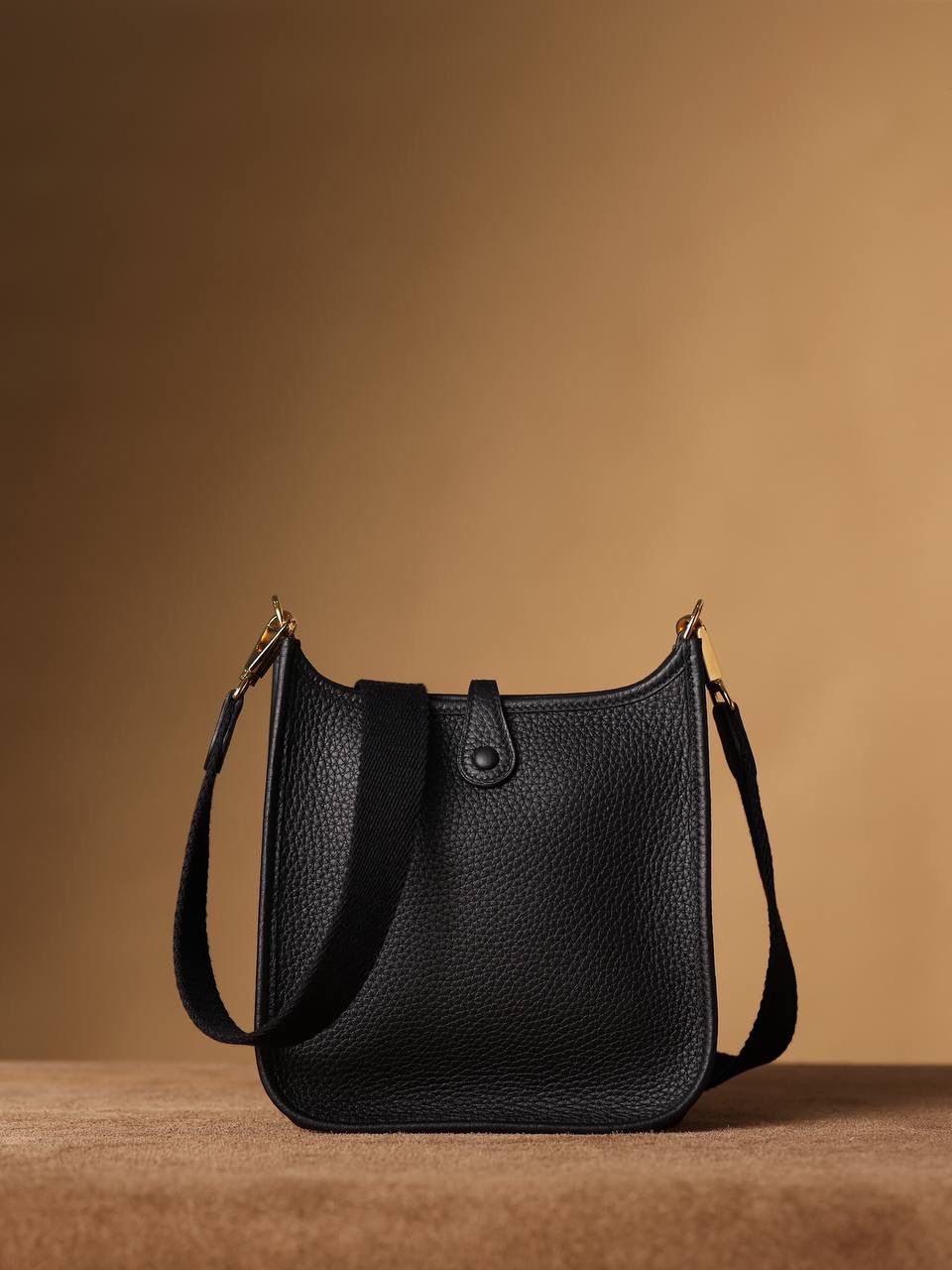 HERMES爱马仕Evelyne 16伊芙琳黑色金扣👜✨ TaurillonMaurice 小公牛皮 尺寸：16*18*5cm 爱马仕Evelyne伊芙琳 Evelyne包的设计灵感来自于一种名为“马鞍袋”的马具袋，这是一种常用于骑手和马车夫的袋子，用于储存和运输马具和其他必需品。 爱马仕将这种马具袋的经典元素与品牌的手工艺传统相结合，打造出了具有时尚感和功能性的包包。 因此，伊芙琳包不仅是一款实用的手提包，同时也代表着品牌深厚的历史和文化传统❤️