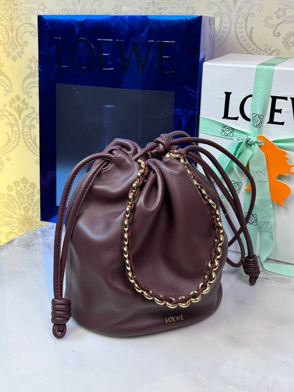 🎈链条款𝙁𝙡𝙖𝙢𝙚𝙣𝙘𝙤 𝙋𝙪𝙧𝙨𝙚水桶羊皮 ——【酒红色】 尺寸：𝟑𝟐-𝟏𝟕-𝟐𝟒𝐜𝐦 编码：062406 👉🏻延续福袋收缩绳褶皱设计，全新推出水桶造型，羊皮包身手感细腻柔软❤️ 👉🏻链条肩带➕皮肩带的双肩带设计，时尚百搭，给足了集美们多样化的选择。肩带可拆卸可调节，磁扣开合，正面烫金𝙇𝙤𝙜𝙤，呈现出高贵典雅的视觉感😍 👉🏻独家背景➕独家品质➕独家全套砖柜礼盒套装，市场高端品质皆在我手✌🏻