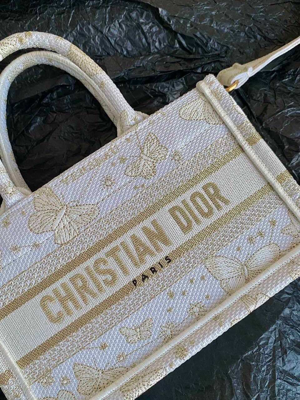 🈶金色蝴蝶迷你 𝗖𝗗 𝗕𝗼𝗼𝗸 𝗧𝗼𝘁𝗲 24圣诞限定🎄 圣诞季这一波𝗗𝗜𝗢𝗥真的稳赢 浪漫的蝴蝶刺绣 象征着自由和转变 高级的配色 精致的造型与细节设计，无不透露出一种温柔而魔法般的美感🪄💕 呜呜真的太好看了，姐妹们必冲！ 21.5×13×7.5cm