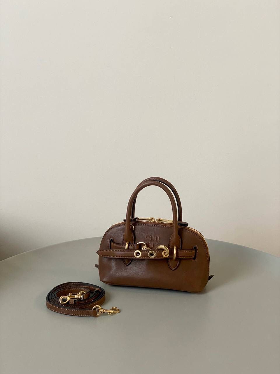 🈶焦糖色，迷你 𝗠𝗶𝘂𝗠𝗶𝘂24秋冬贝壳包 年度爆炸款来啦 | 真心被夸爆 没有过分夸张的设计，有着时髦且个性的圆弧包型，形似贝壳，看着很轻松又舒适一点也不会给人压力 双向拉链在保证实用性的同时让它充满了复古的调性，搭配上腰带式设计细节，时髦有态度 面料手感软糯，拎在手上可以切确感受到高级质感 迷你：8×13×21cm #F0022m 小号：16.5x28x10cm 大号：33x17x11cm