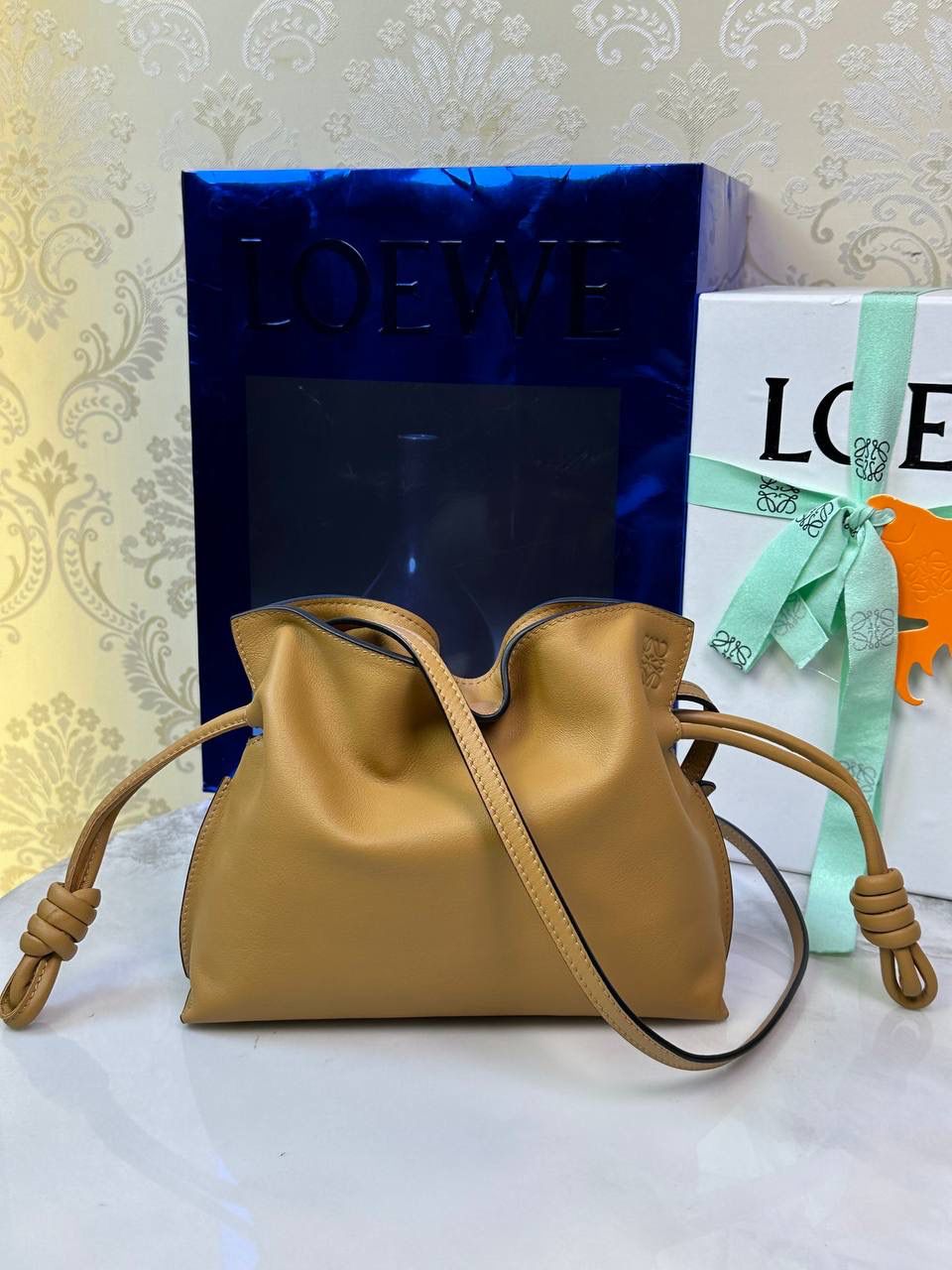 Flamenco clutch ✦迷你✦ 尺寸：𝟐𝟐.𝟓-𝟏𝟖-𝟗𝐜𝐦 型号：052030 棕色 ❤️mini flamenco clutch bag 可手拿亦可优雅斜挎 云朵般温暖亦轻盈的造型如此简单，💯耐看💯不会out的款式！ ❤️包袋采用进口小牛皮，手感如羊皮般细腻柔软，却比羊皮更加结实耐用，麂皮内衬 ❤️品牌标志性绳结设计，收紧袋口就是小福袋造型，超Q，看着不大实际超会装😇