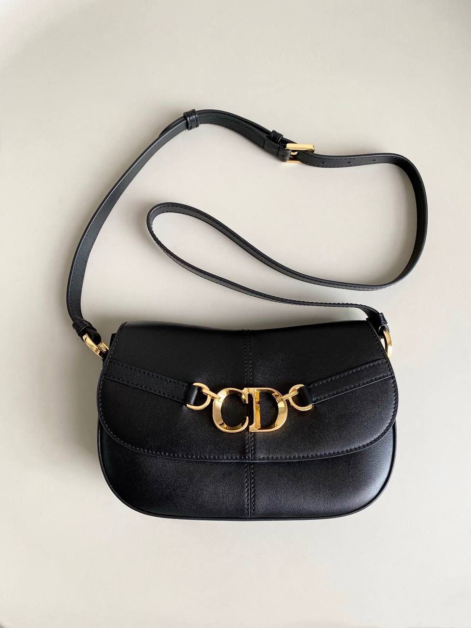 🈶黑色 𝗗𝗶𝗼𝗿 𝗯𝗲𝘀𝗮𝗰𝗲 马鞍包小号 相比较之前的bobby来说 这个版型会更大一些，皮质更柔软一些 正面是经典的CD扣，超级复古 背面仍然是延续了D家的风格 有个内侧袋，可以放手机或放卡 翻盖按扣式设计，里面还有个拉链隔层 非常实用好收纳 大小也很俏皮，容量足够日常 斜挎 肩背 腋下都可以！ 24×15×6cm #8010m