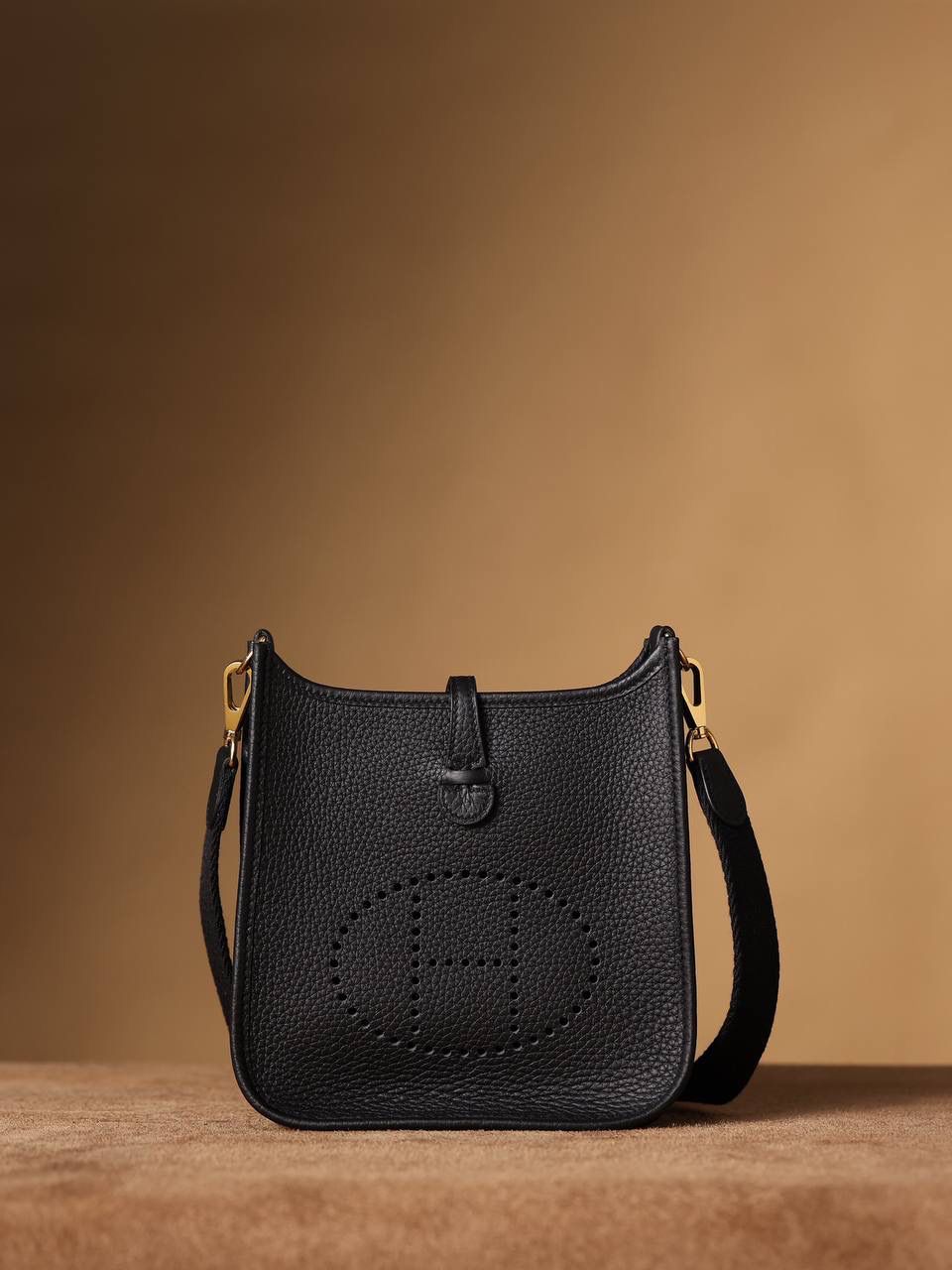 HERMES爱马仕Evelyne 16伊芙琳黑色金扣👜✨ TaurillonMaurice 小公牛皮 尺寸：16*18*5cm 爱马仕Evelyne伊芙琳 Evelyne包的设计灵感来自于一种名为“马鞍袋”的马具袋，这是一种常用于骑手和马车夫的袋子，用于储存和运输马具和其他必需品。 爱马仕将这种马具袋的经典元素与品牌的手工艺传统相结合，打造出了具有时尚感和功能性的包包。 因此，伊芙琳包不仅是一款实用的手提包，同时也代表着品牌深厚的历史和文化传统❤️