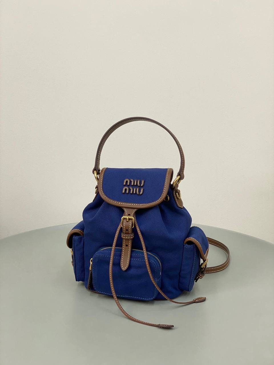 🈶帆布蓝，小号 𝐌𝐢𝐮𝐌𝐢𝐮 双肩包 喔噻！缪缪终于出双肩包了！ 超级经典的款，配色也是无敌了 多个口袋设计非常复古学院风，青春洋溢！ 五金质感超绝，带有微微做旧的复古磨砂感 这种材质耐用度极高 帆布版俩个颜色都好看！海军蓝，甜酷不失高级感 总的来说夏天就是要拿个亮色的出游 轻便实用 小号：18×22×11.5cm #F0060m 大号：25x29x12.5cm