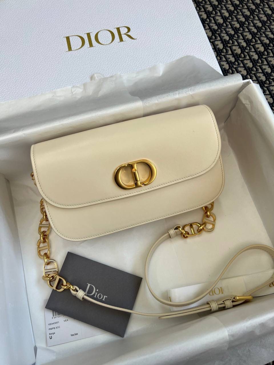 30 MONTAIGNE AVENUE 手袋 灰象牙色光面牛皮革👜✨ 独家渠道货 独家蒙田腋下包白色珐琅扣 尺寸：22.5 x 12.5 x 6.5 厘米 这款 30 Montaigne Avenue 手袋采用典雅的设计，提升此经典系列的格调。 采用黑色光面牛皮革精心制作，圆角翻盖曲线精致，饰以复古金色饰面金属 CD 扣环，灵感源自 Christian Dior 香水瓶的封口。 背面饰以压花 30 Montaigne 标志，搭配由金色饰面金属和与皮革同色调的珐琅链环交替组成的经典链条。 褶层设计，空间宽敞，廓形精致，可手提，肩背或斜挎。