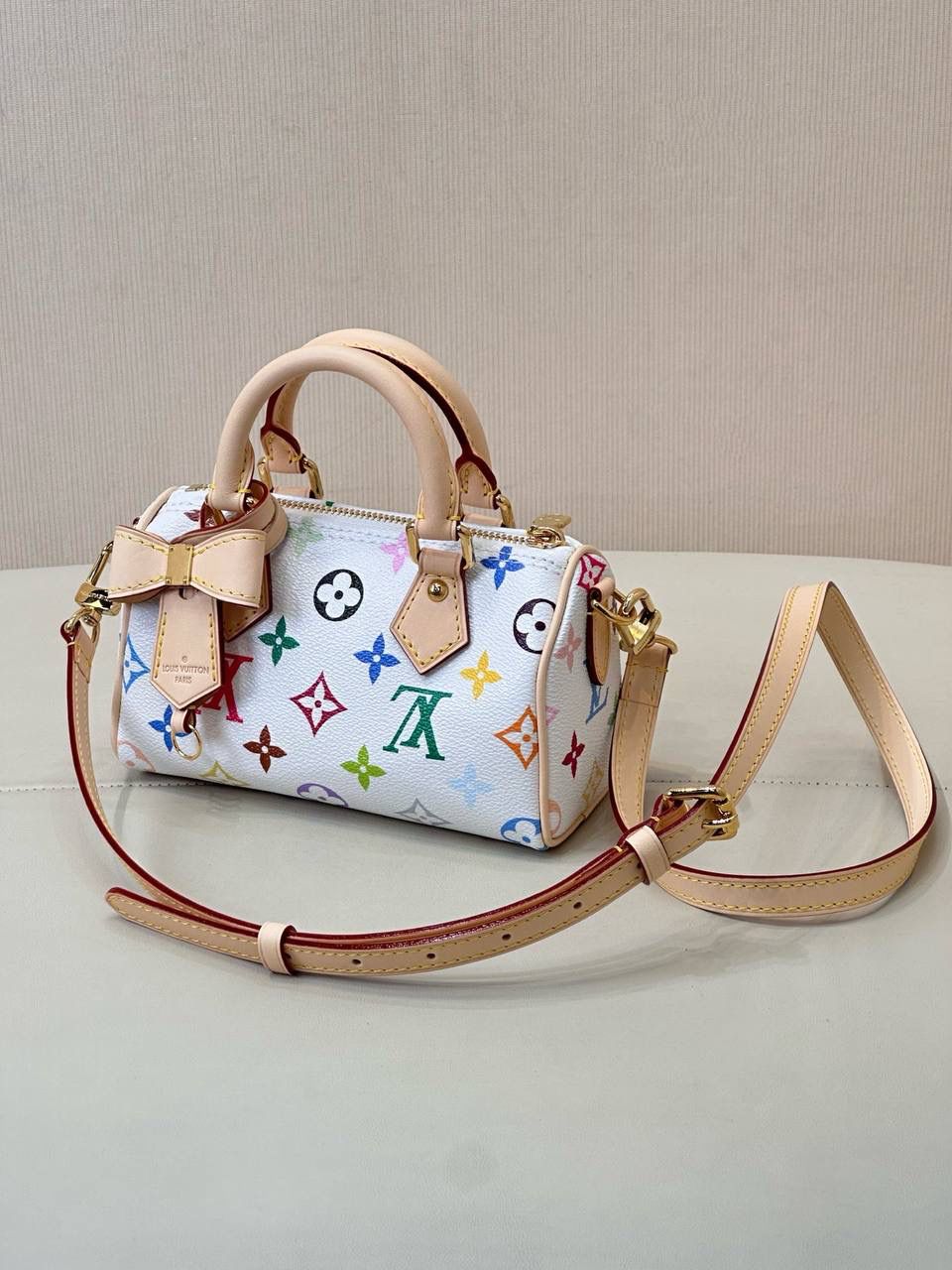 LV村上隆联名白三彩Nano Speedy来啦！姐妹们快看这个神仙包包！👜🌈 白色打底+彩色老花图案，配上祖传小锁头钥匙包，简直是《Mean Girls》千禧辣妹的标配！全新数码印花绝绝子，太阳花和熊猫都像要跳出来，阳光下自带ins滤镜特效！别看它巴掌大，手机口红💄钥匙全塞得下，从此打脸那些说mini包不实用的人！ 尺寸：16-10-7.5cm