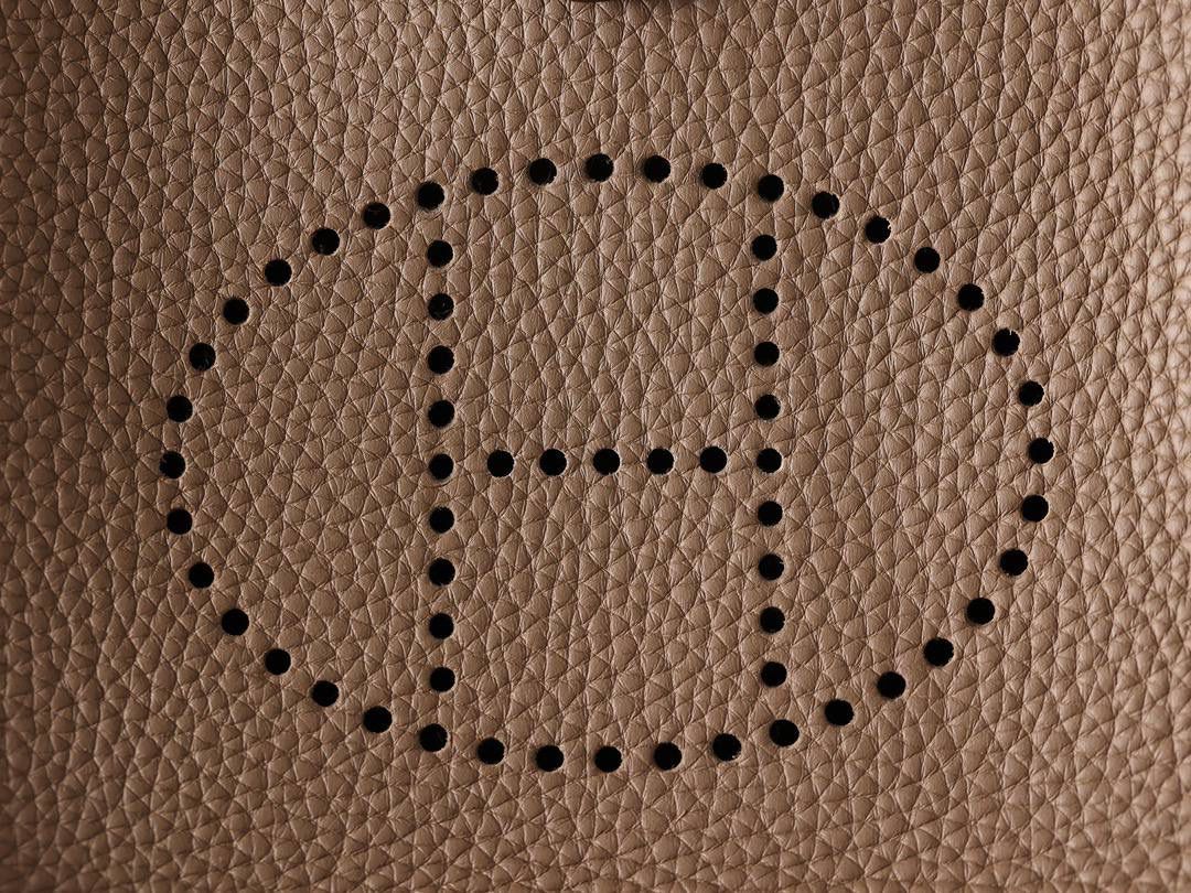 HERMES爱马仕Evelyne 16伊芙琳大象灰金扣👜✨ TaurillonMaurice 小公牛皮 尺寸：16*18*5cm 爱马仕Evelyne伊芙琳 Evelyne包的设计灵感来自于一种名为“马鞍袋”的马具袋，这是一种常用于骑手和马车夫的袋子，用于储存和运输马具和其他必需品。 爱马仕将这种马具袋的经典元素与品牌的手工艺传统相结合，打造出了具有时尚感和功能性的包包。 因此，伊芙琳包不仅是一款实用的手提包，同时也代表着品牌深厚的历史和文化传统❤️