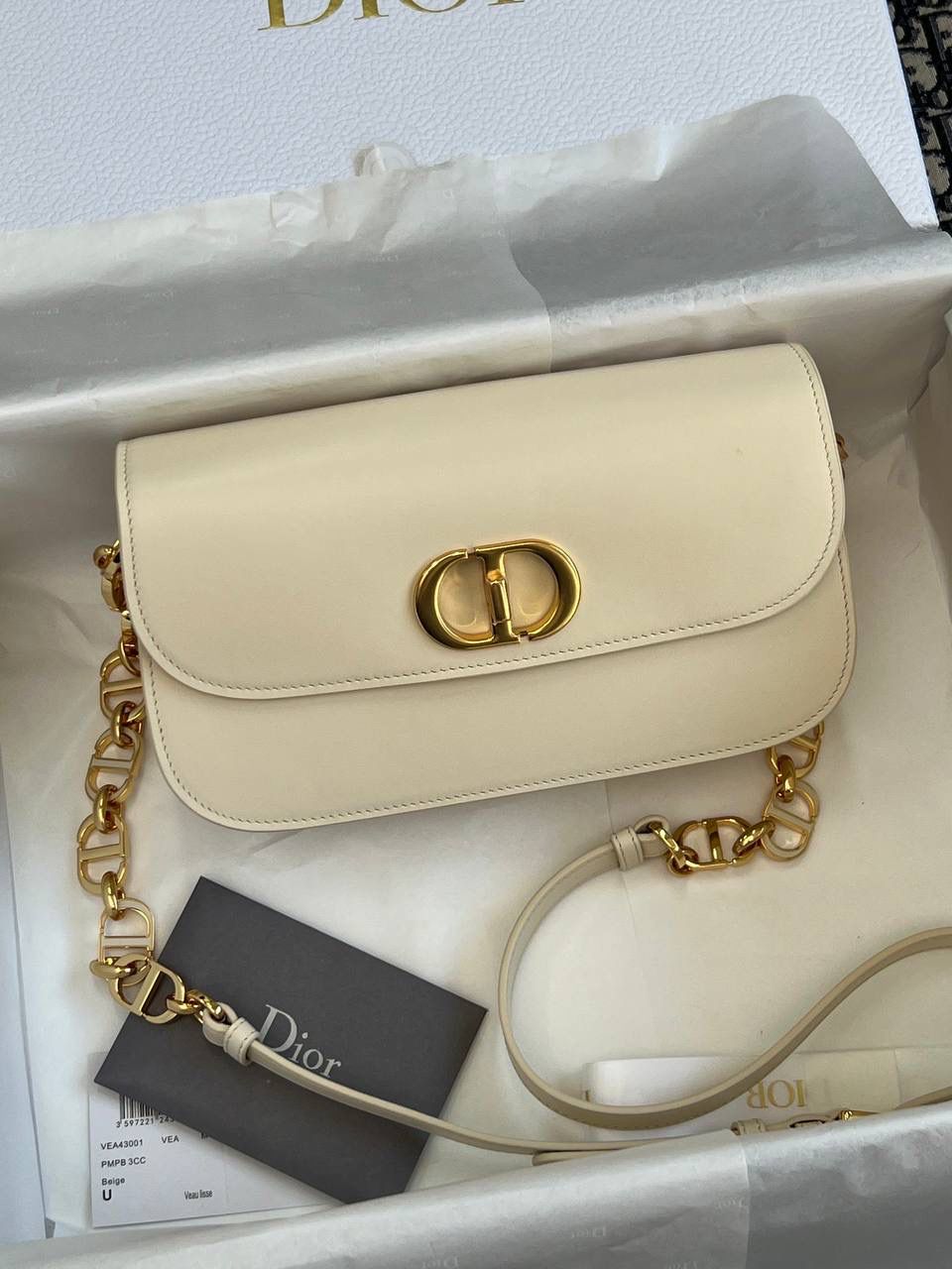 30 MONTAIGNE AVENUE 手袋 灰象牙色光面牛皮革👜✨ 独家渠道货 独家蒙田腋下包白色珐琅扣 尺寸：22.5 x 12.5 x 6.5 厘米 这款 30 Montaigne Avenue 手袋采用典雅的设计，提升此经典系列的格调。 采用黑色光面牛皮革精心制作，圆角翻盖曲线精致，饰以复古金色饰面金属 CD 扣环，灵感源自 Christian Dior 香水瓶的封口。 背面饰以压花 30 Montaigne 标志，搭配由金色饰面金属和与皮革同色调的珐琅链环交替组成的经典链条。 褶层设计，空间宽敞，廓形精致，可手提，肩背或斜挎。