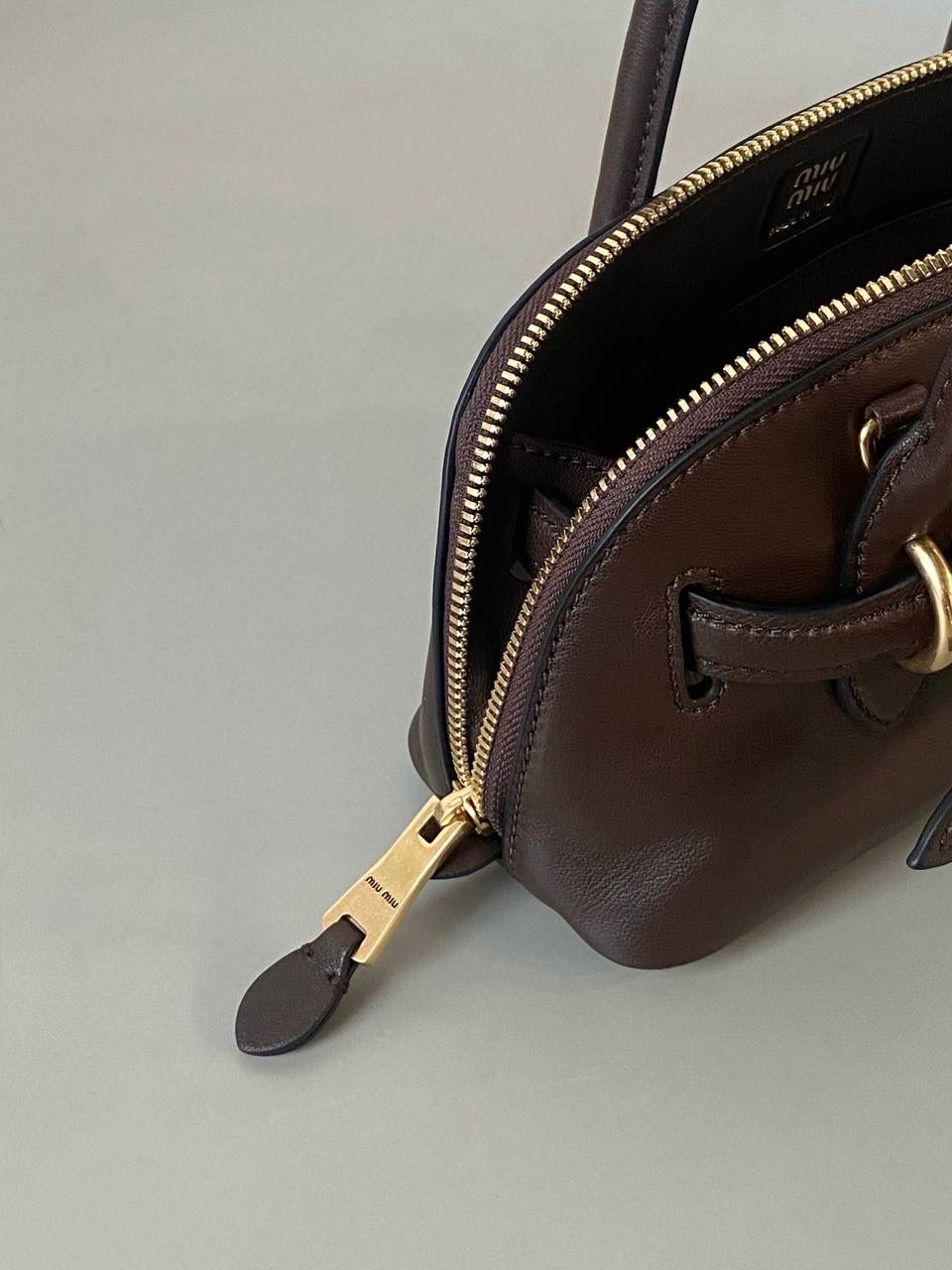 🈶石南木色，迷你 𝗠𝗶𝘂𝗠𝗶𝘂24秋冬贝壳包 年度爆炸款来啦 | 真心被夸爆 没有过分夸张的设计，有着时髦且个性的圆弧包型，形似贝壳，看着很轻松又舒适一点也不会给人压力 双向拉链在保证实用性的同时让它充满了复古的调性，搭配上腰带式设计细节，时髦有态度 面料手感软糯，拎在手上可以切确感受到高级质感 迷你：8×13×21cm #F0022m 小号：16.5x28x10cm 大号：33x17x11cm