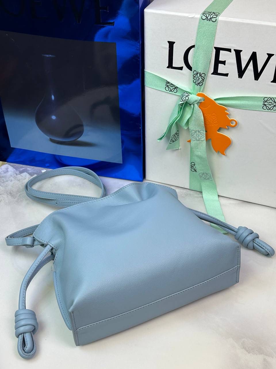 Flamenco clutch-NEW ✦迷你✦ 尺寸：𝟐𝟐.𝟓-𝟏𝟖-𝟗𝐜𝐦 型号：052030灰蓝色 ❤️mini flamenco clutch bag 可手拿亦可优雅斜挎 云朵般温暖亦轻盈的造型如此简单，💯耐看💯不会out的款式！ ❤️包袋采用进口小牛皮，手感如羊皮般细腻柔软，却比羊皮更加结实耐用，麂皮内衬 ❤️品牌标志性绳结设计，收紧袋口就是小福袋造型，超Q，看着不大实际超会装😇