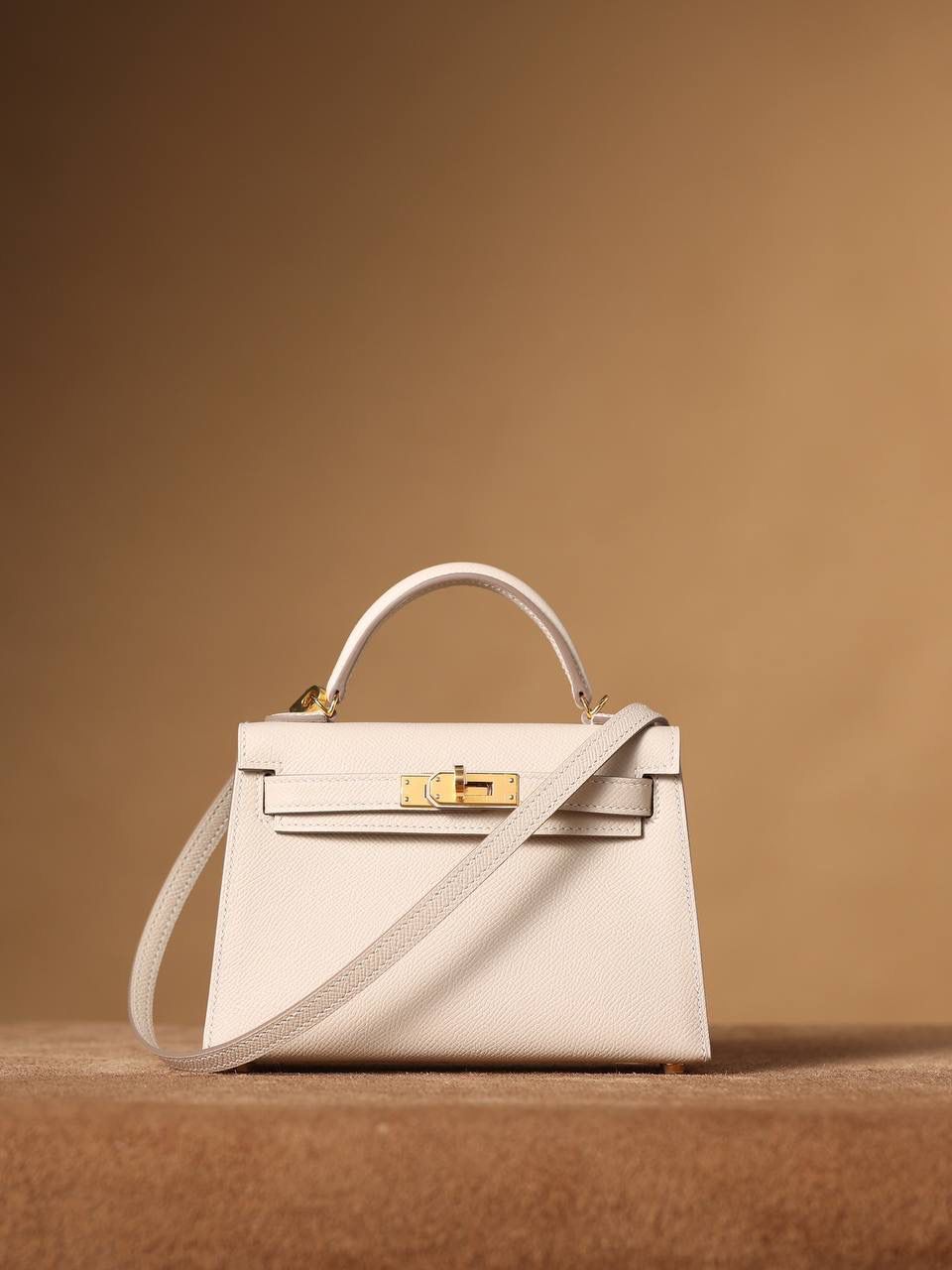 HERMES 爱马仕 Mini Kelly 二代 👜✨ Mini Kelly 二代 奶昔白金扣 高清实拍图 尺寸：19*12*6cm Hermès爱马仕是世界著名的奢侈品品牌，1837年由Thierry Hermès创立于法国巴黎。爱马仕早年以制造高级马具起家，迄今已有180年的悠久历史。 其整个品牌从整体到细节以及专卖店，都弥漫着浓郁的以马文化为中心的深厚底蕴🎀